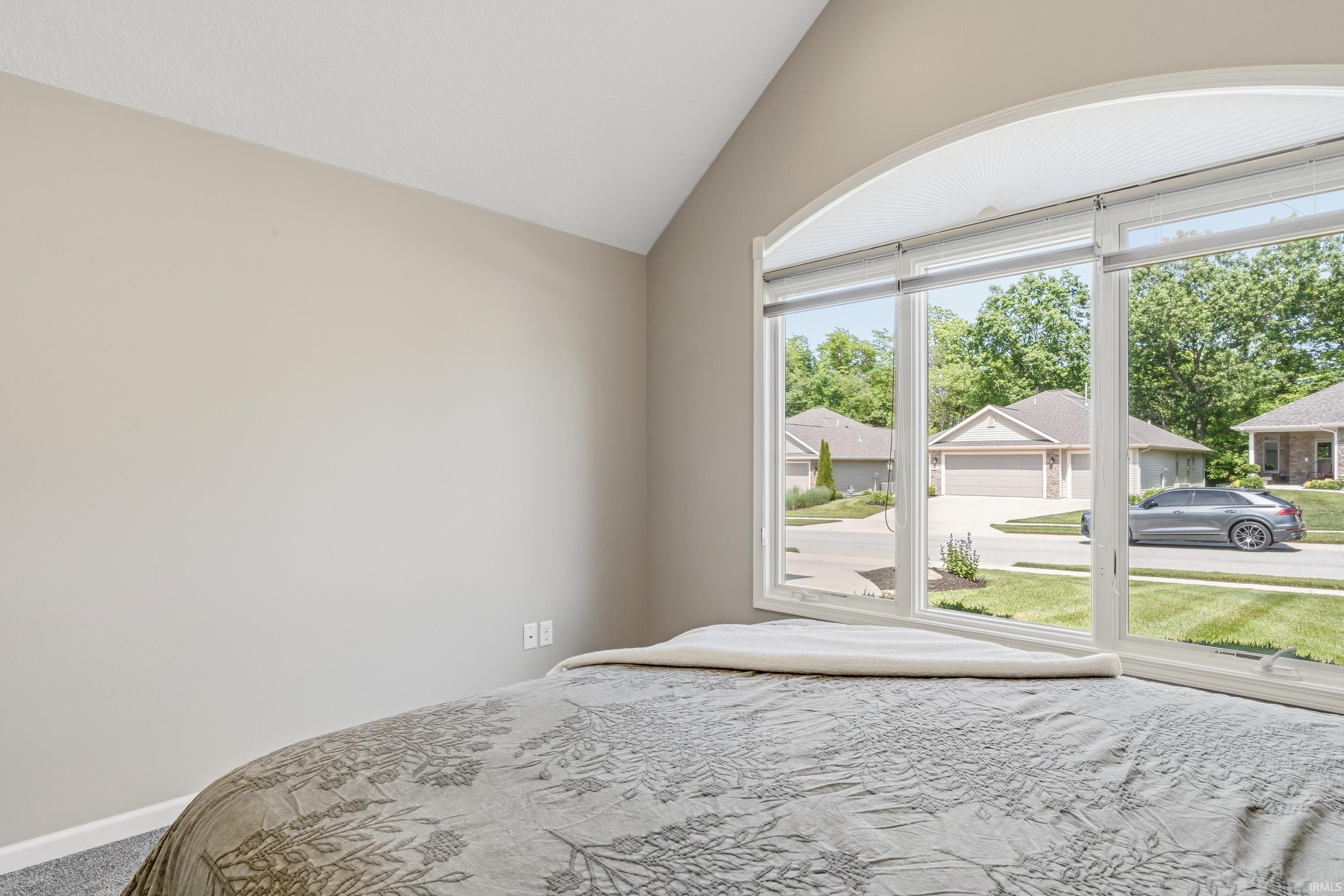 Vaulted ceiling room featuring a large arched window with horizontal blinds