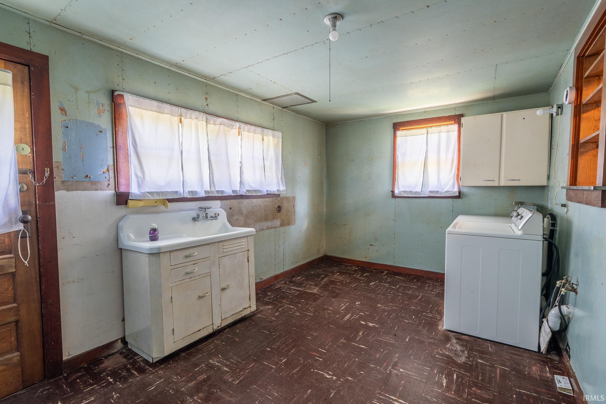 Utility room featuring a built-in sink cabinet, recessed wall shelving, and overhead cabinetry
