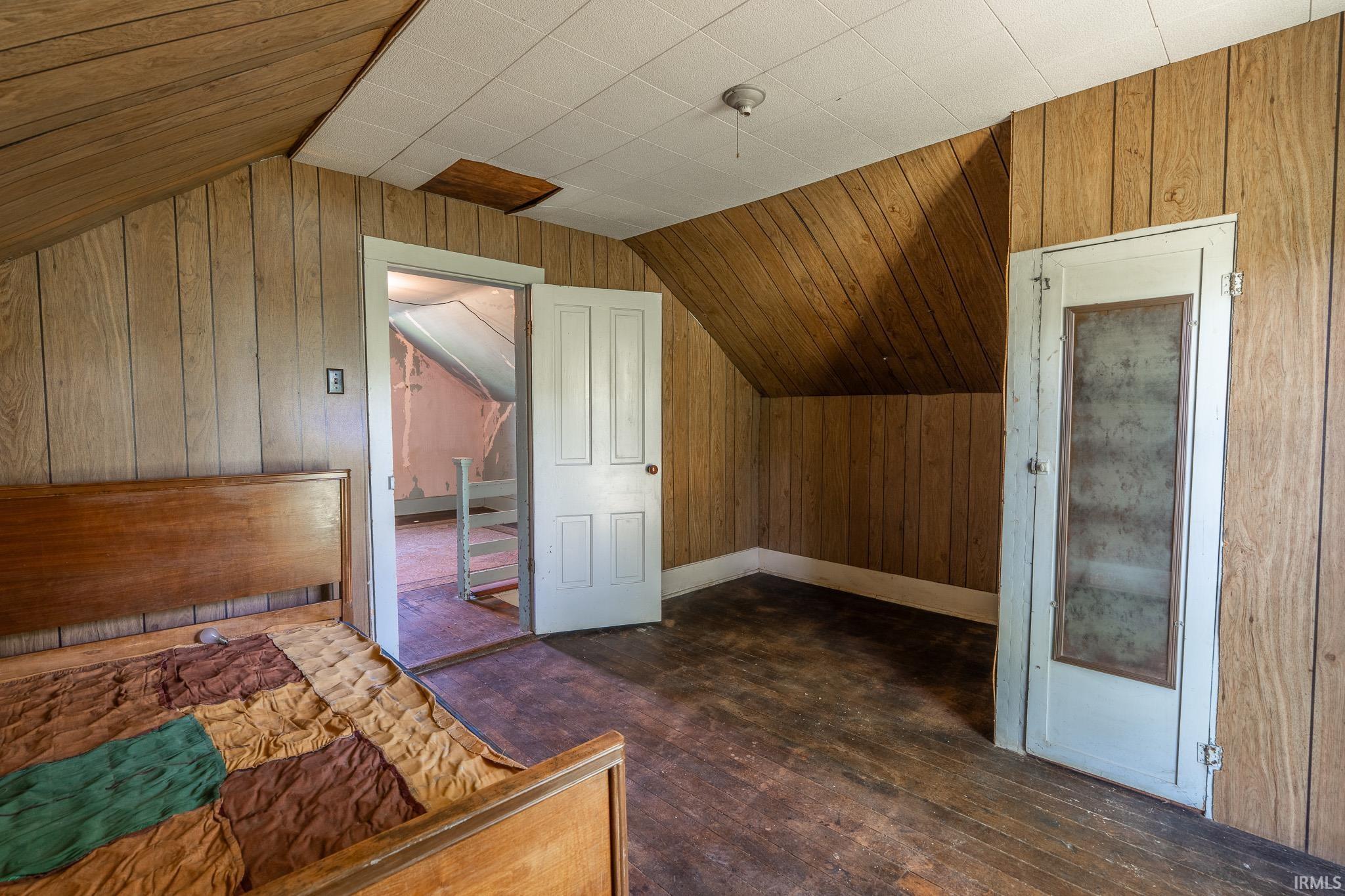 Wood-finish paneling and wood-finish flooring define this space, featuring an angled ceiling line