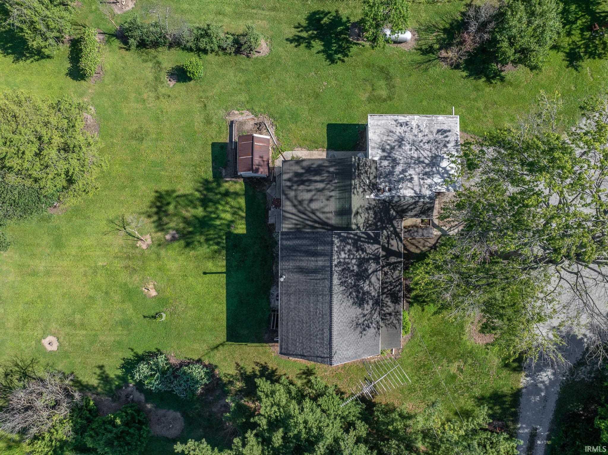 Overhead view showcasing the property's expansive green lawn, mature trees, and a detached outbuilding