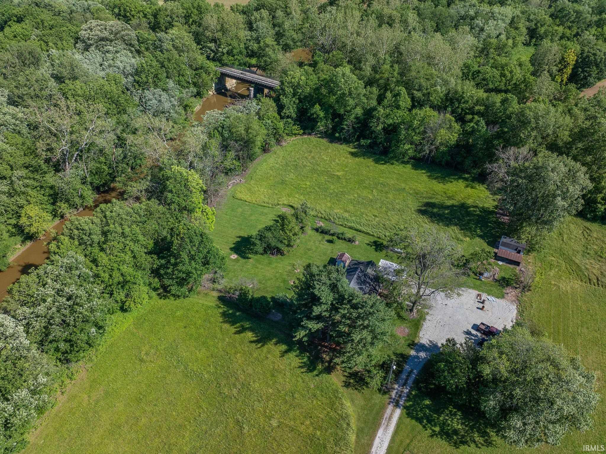 Expansive property featuring a gravel driveway, a main residence, an outbuilding, and a large grassy area