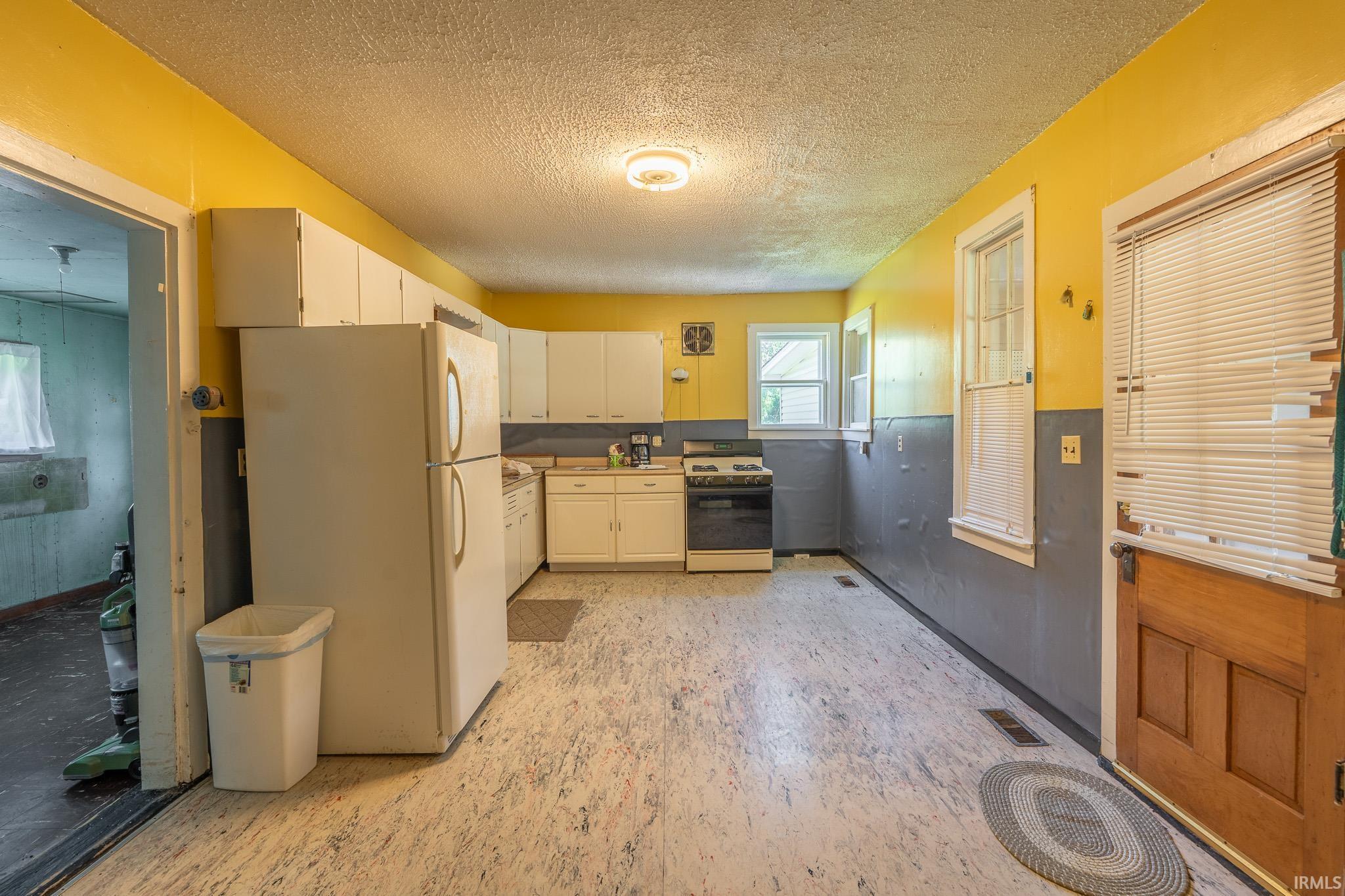Kitchen featuring white cabinetry, a white refrigerator, and a black range