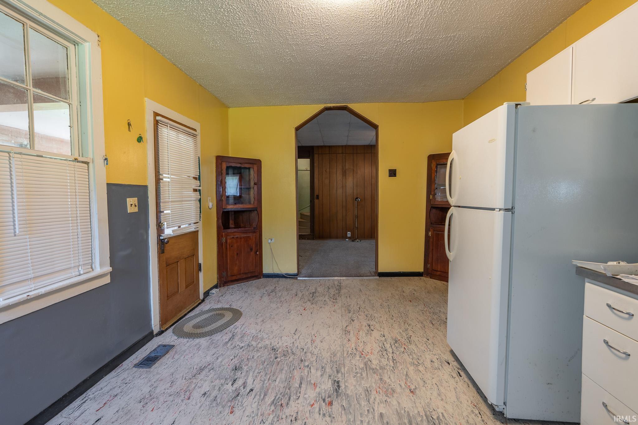 Room featuring white upper cabinetry, a white double-door refrigerator, and wood-finish corner display cabinets