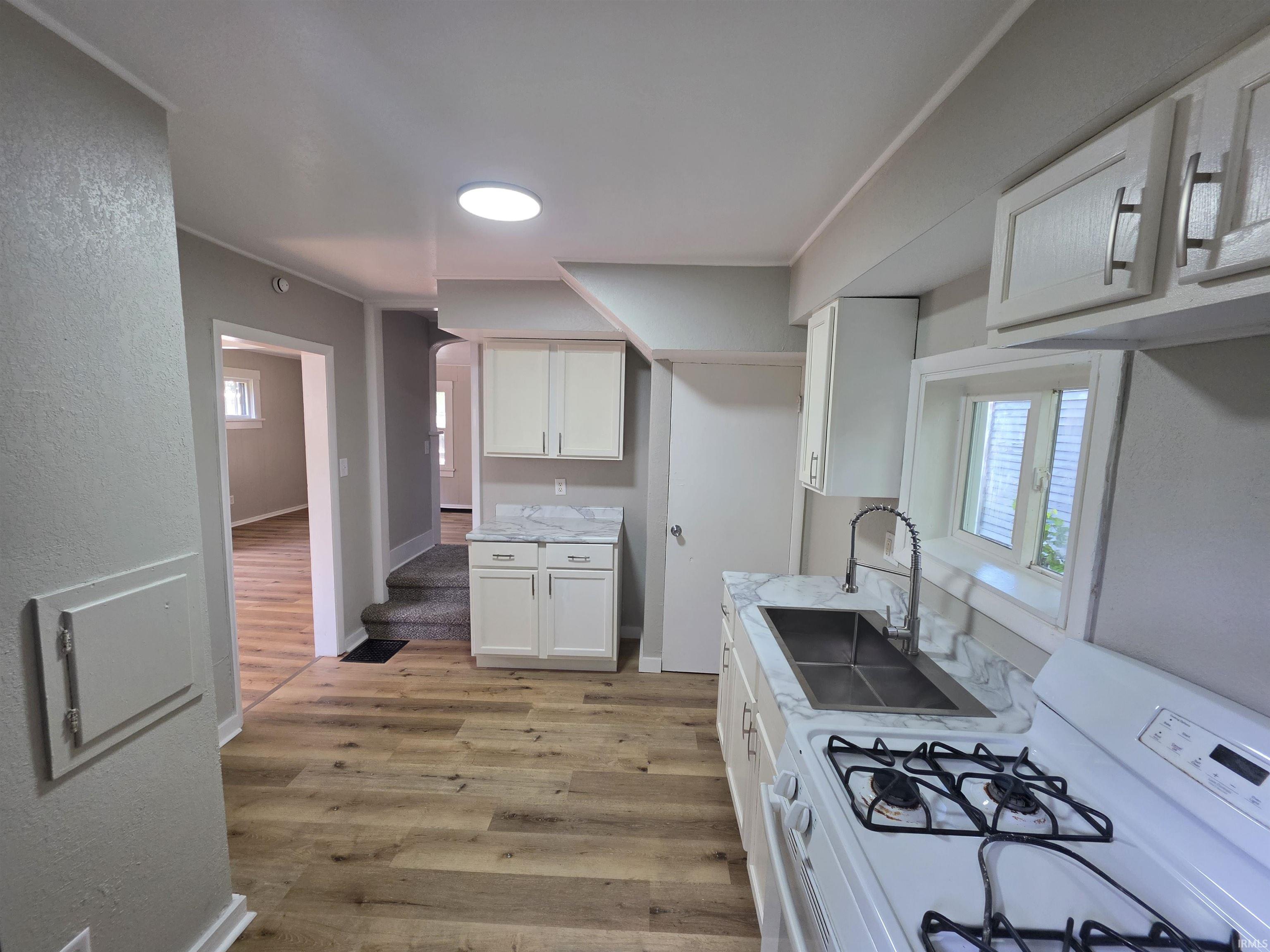 Kitchen featuring wood-finish flooring and white cabinetry
