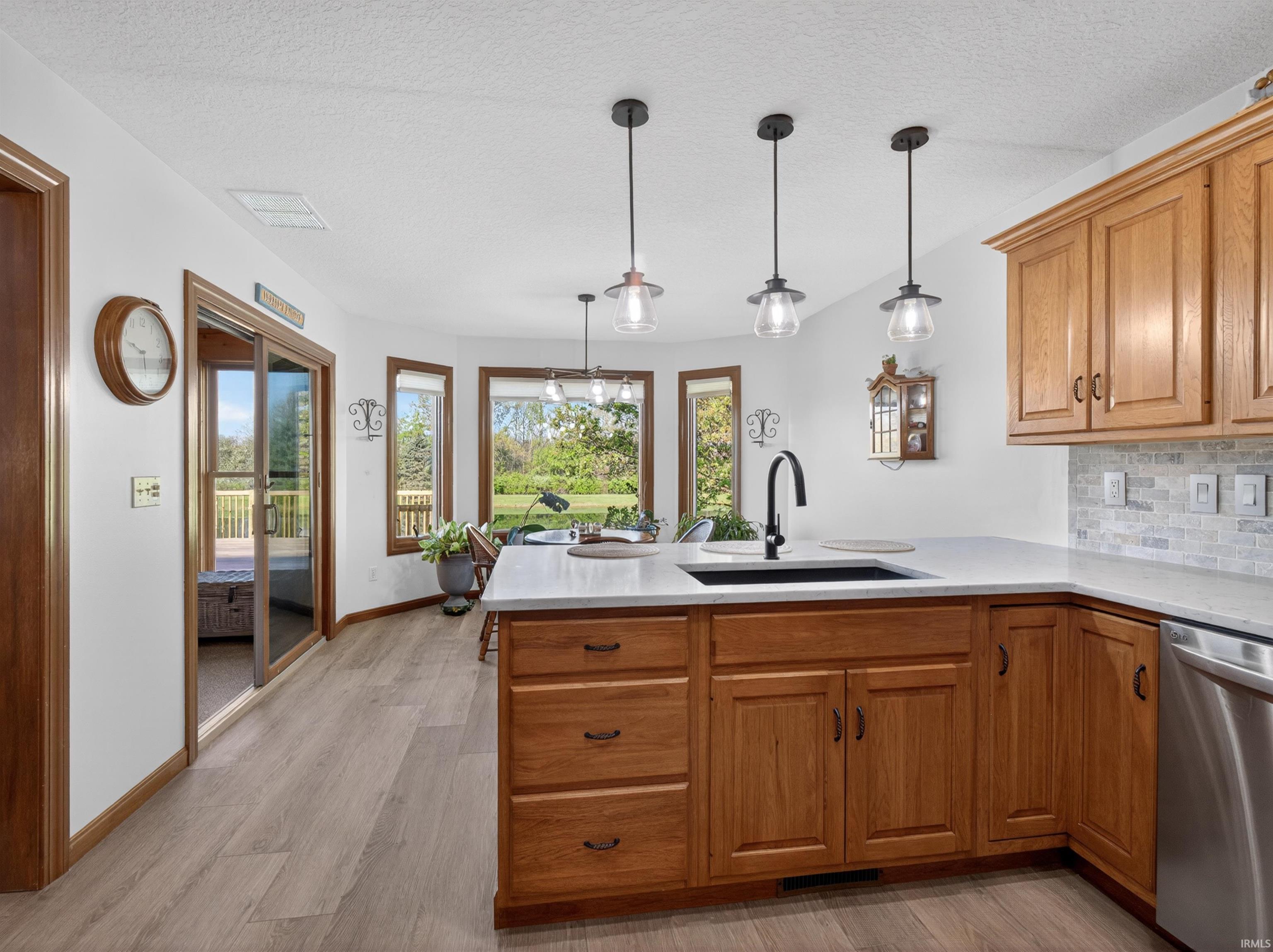 Kitchen featuring NEW RESILIENT PLANK flooring, STAINED wood cabinetry, QUARTZ countertops, and a tile backsplash WITH CUSTOMIZED SWITCHES
