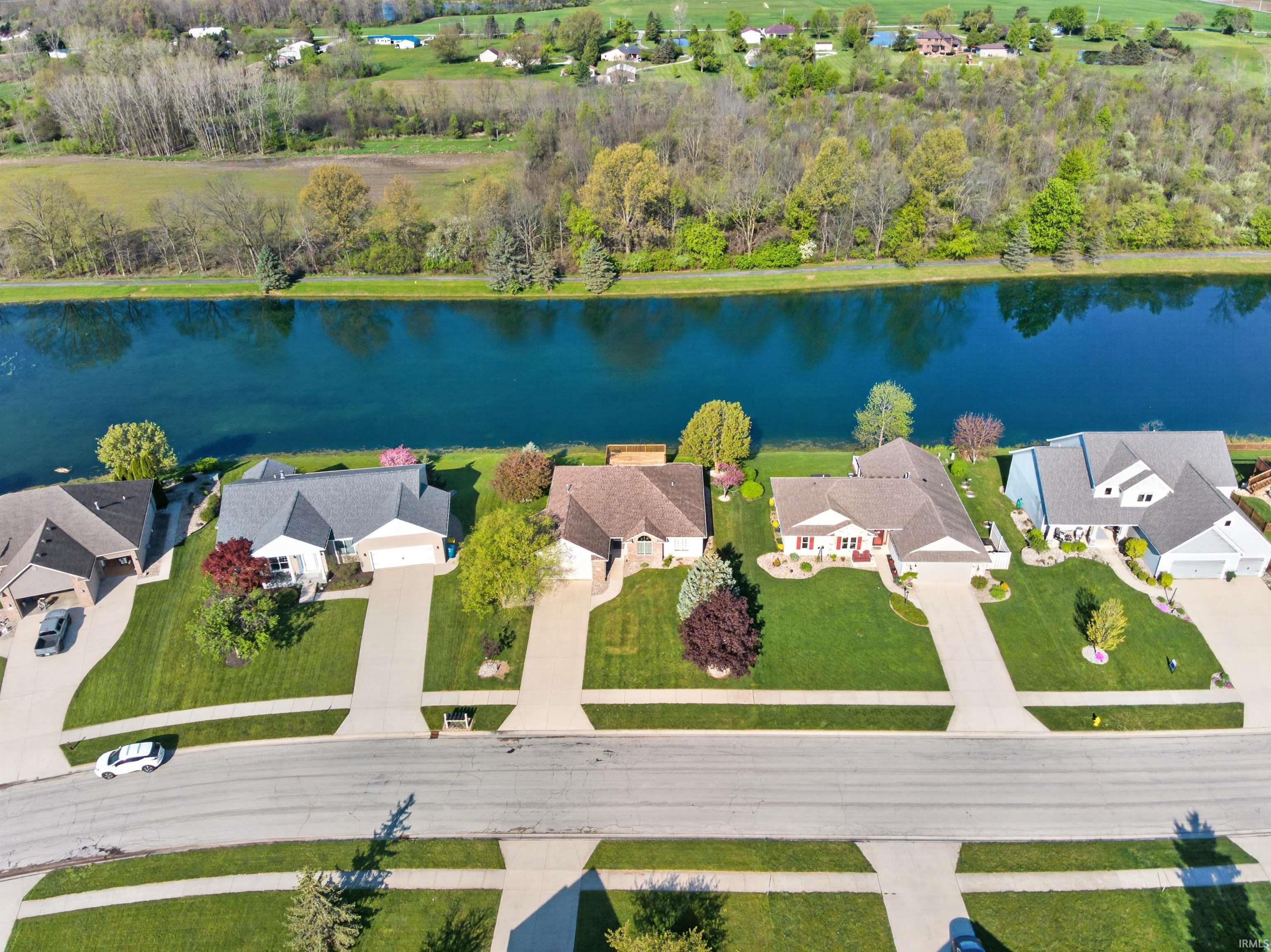 Aerial perspective showcasing a WIDE paved residential street with well-maintained lawns side walks no above ground electric pools wires.