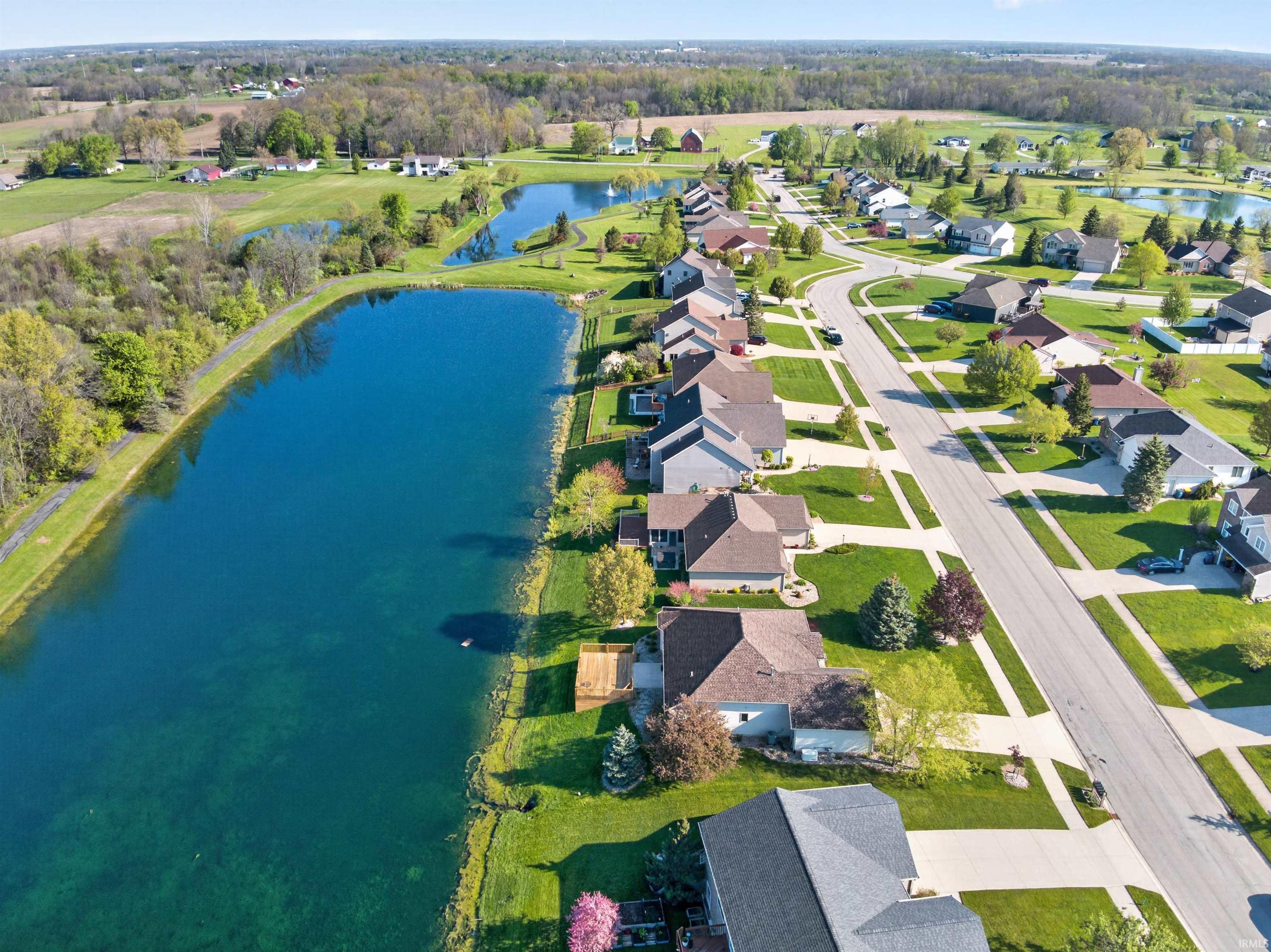 Residential community featuring a curved street, individual homes with varying rooflines, and green lawns