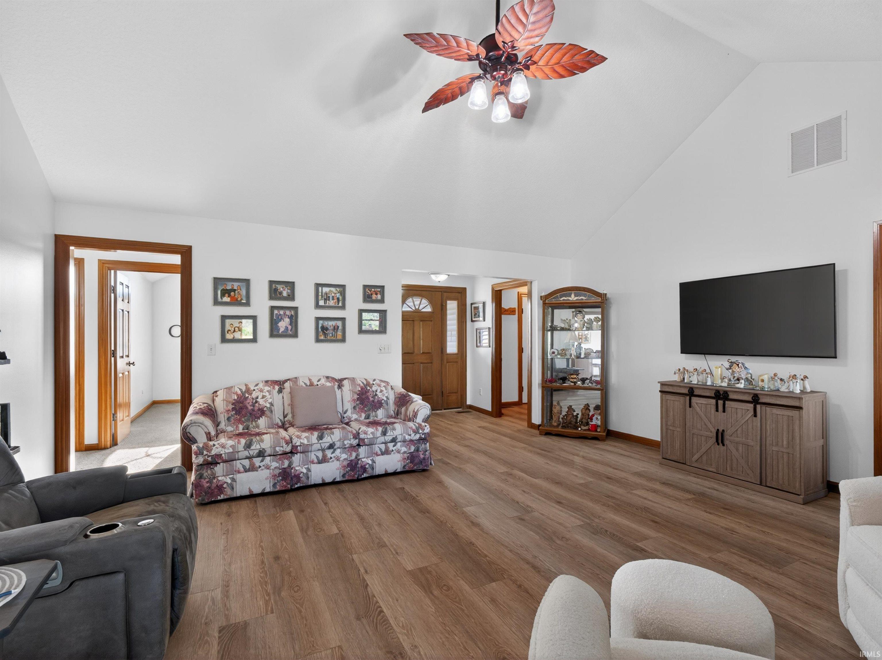 Spacious living area featuring a vaulted ceiling and wood-finish flooring