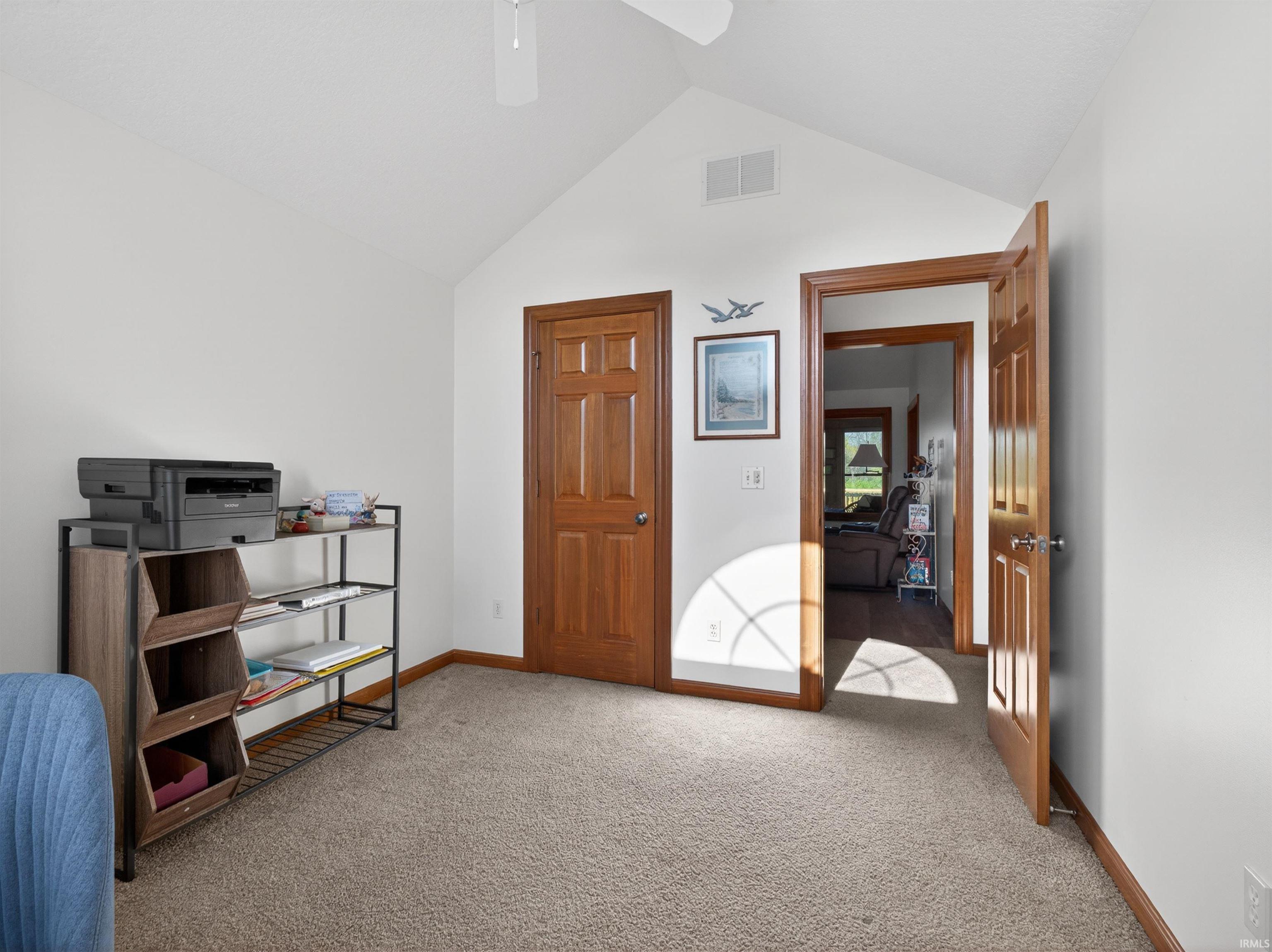 Carpeted room featuring a vaulted ceiling and a ceiling fan
