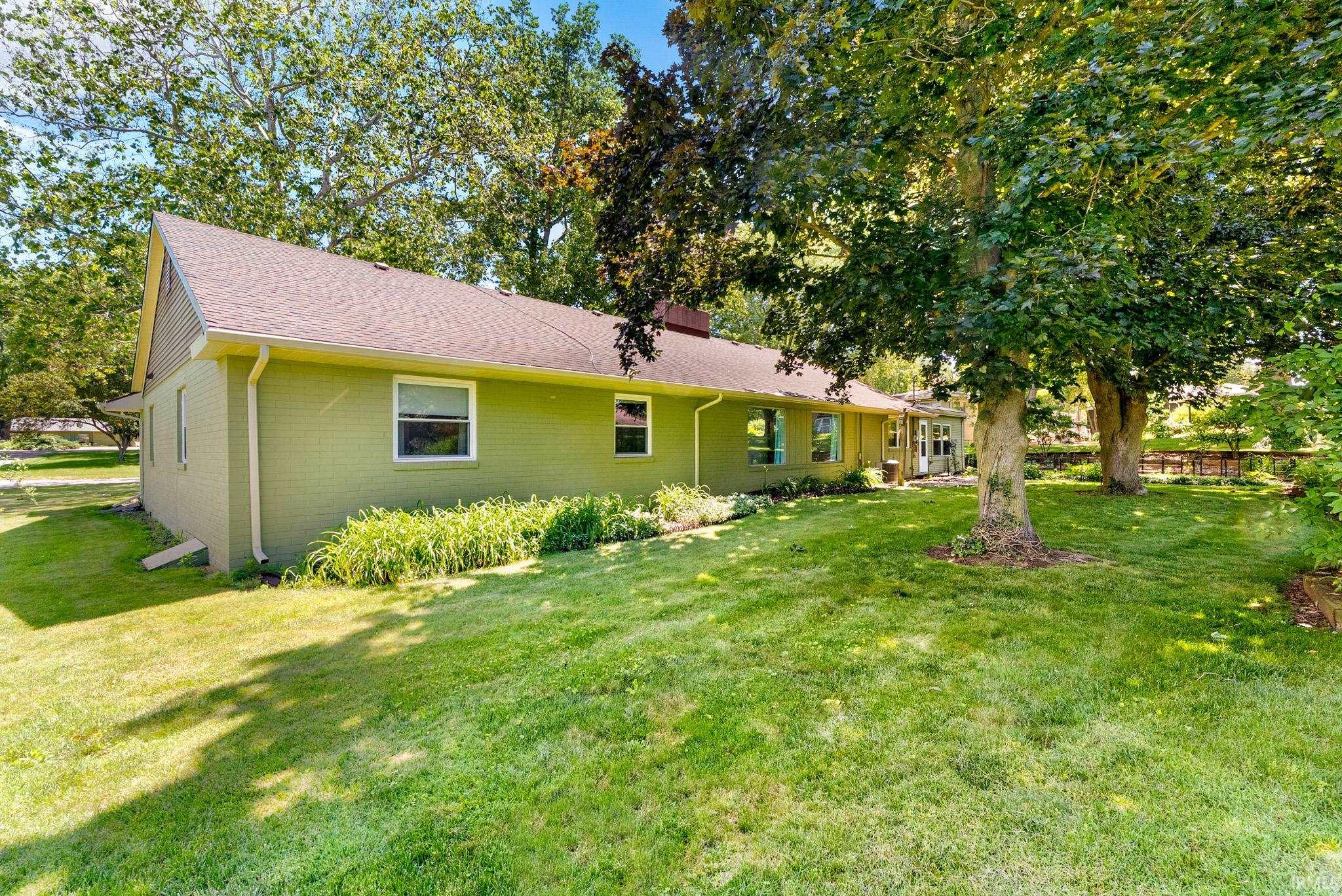 Expansive rear yard featuring mature trees, manicured lawn, and perimeter landscaping