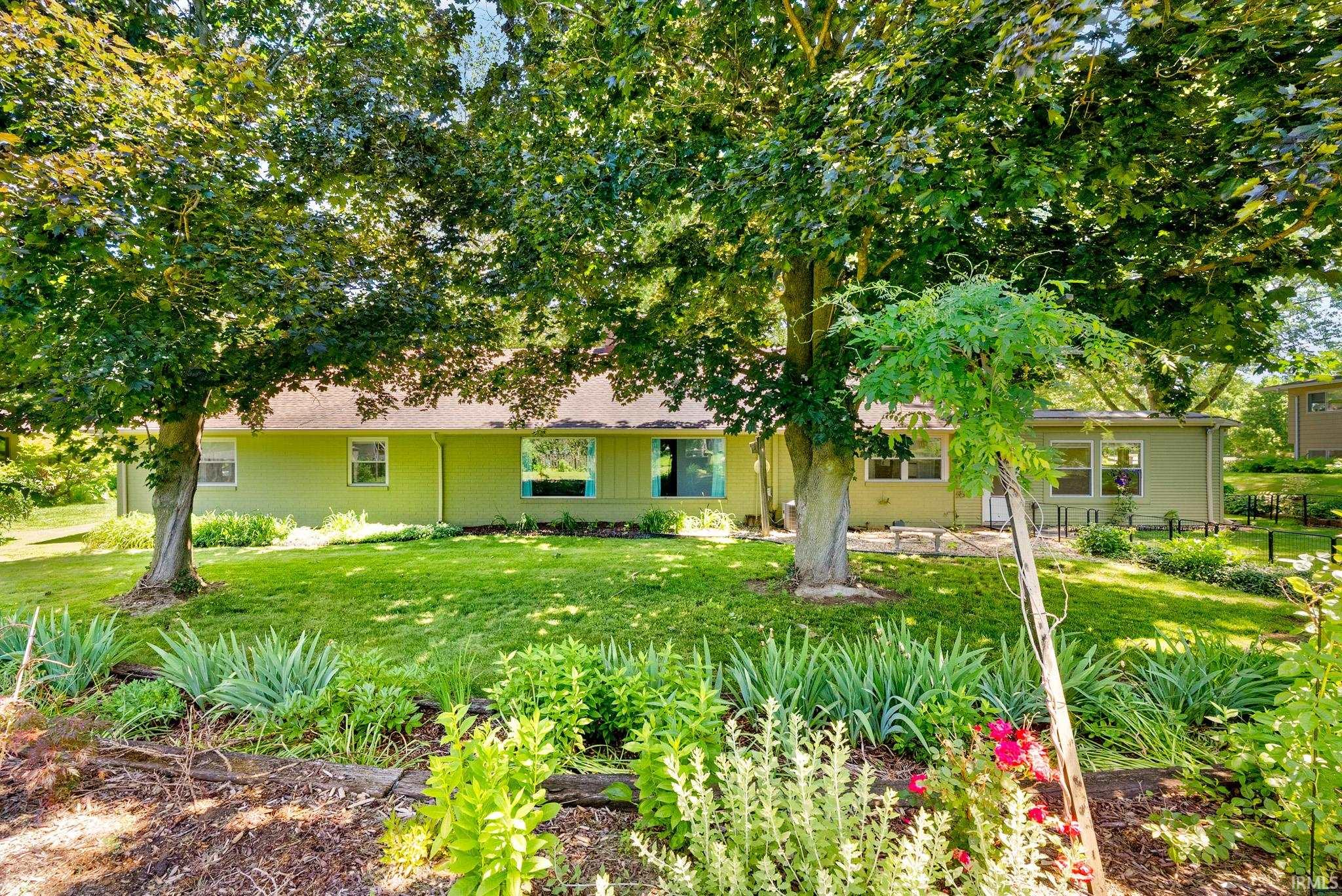 Expansive green lawn with mature trees and established garden beds