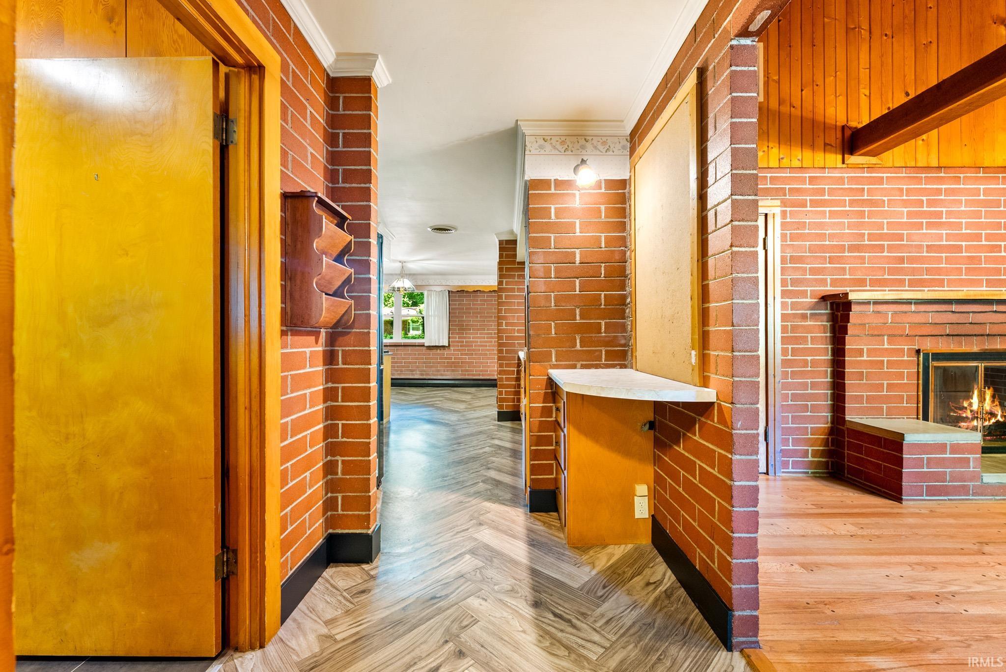 Exposed brick interior walls throughout, wood-finish flooring, a wood-paneled ceiling, and a prominent brick fireplace with a raised hearth