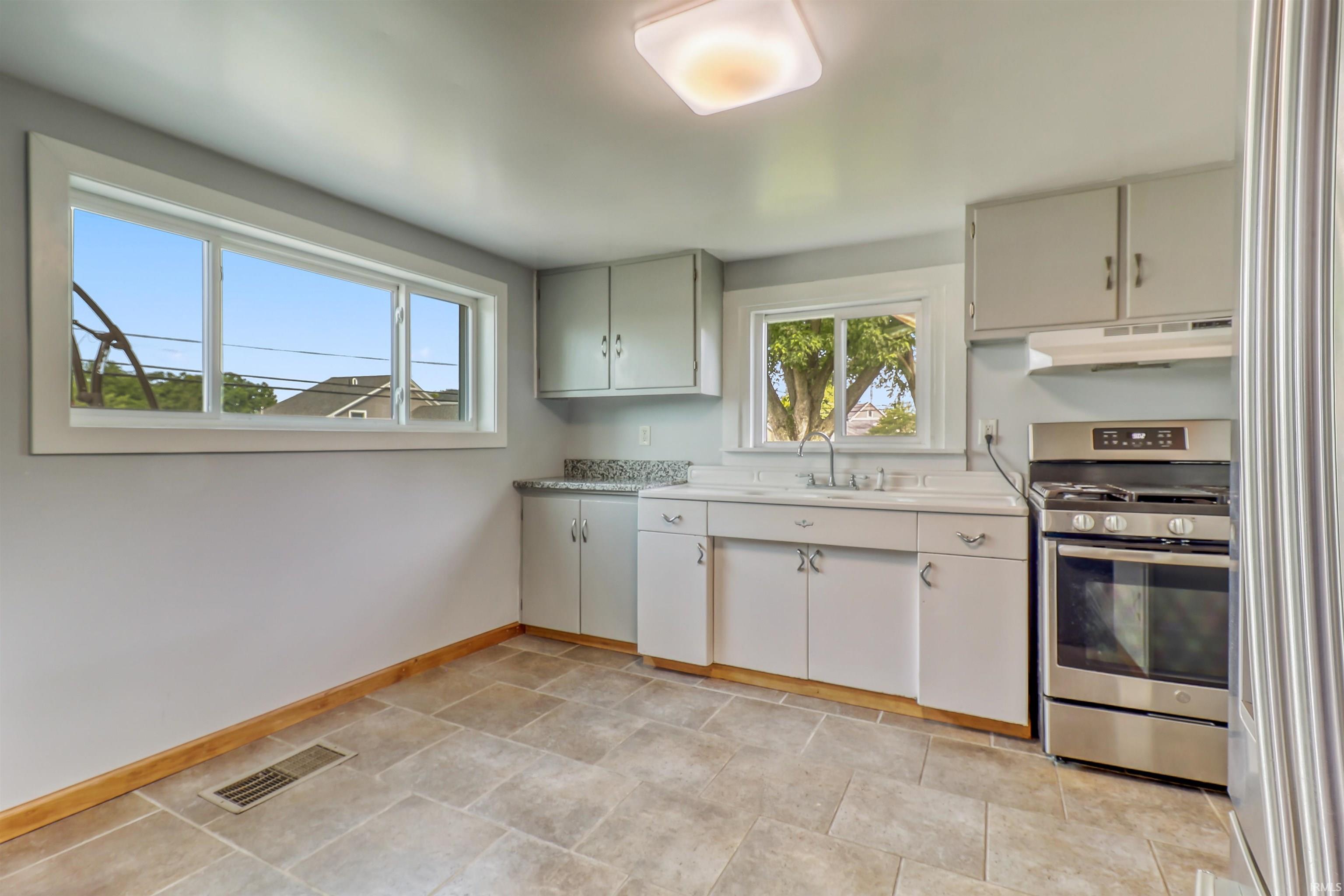 Kitchen featuring a stainless steel range, gray cabinetry, a single basin sink, and granite-look countertops