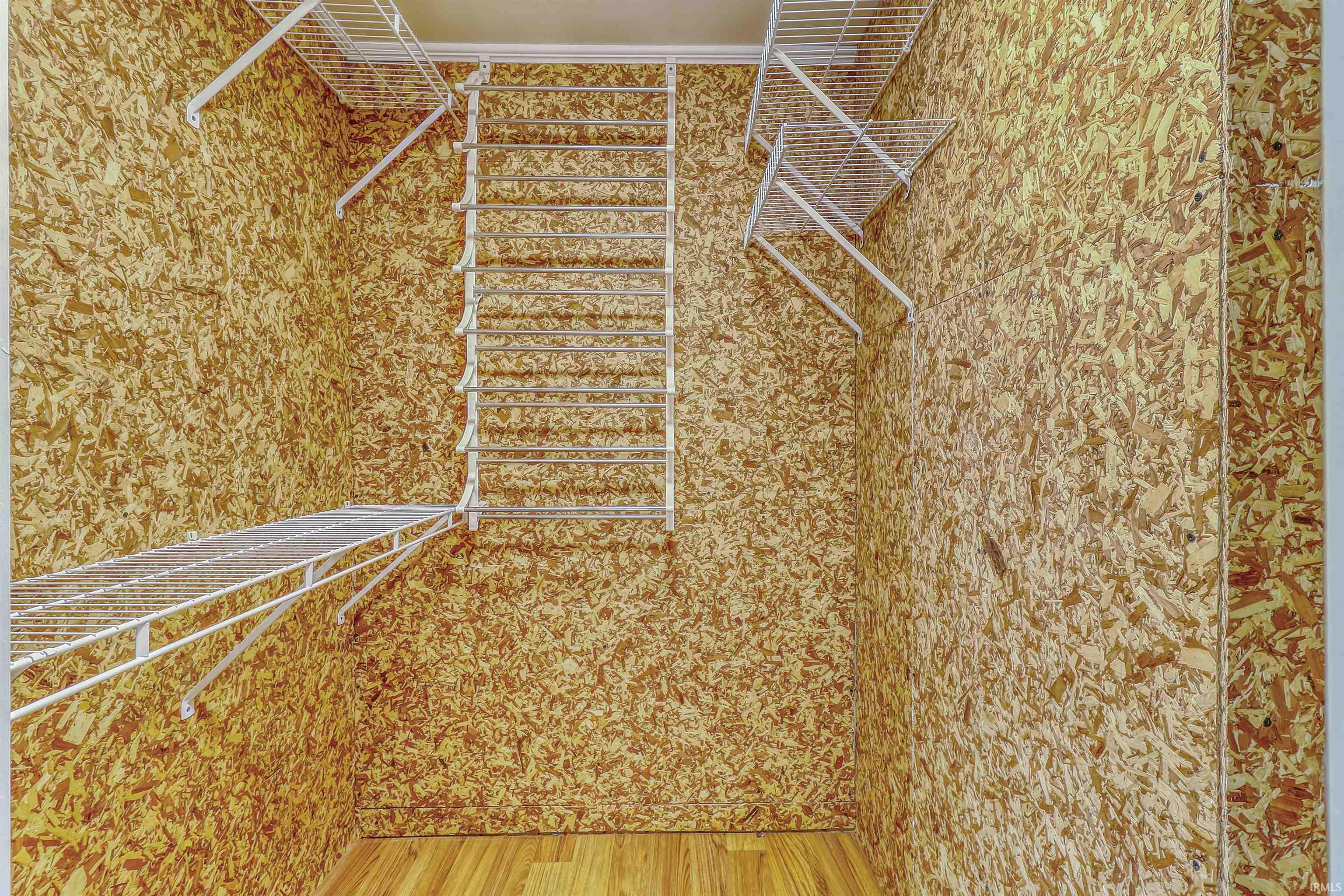 Compact closet featuring wire shelving, wire hanging rods, and wood-finish flooring