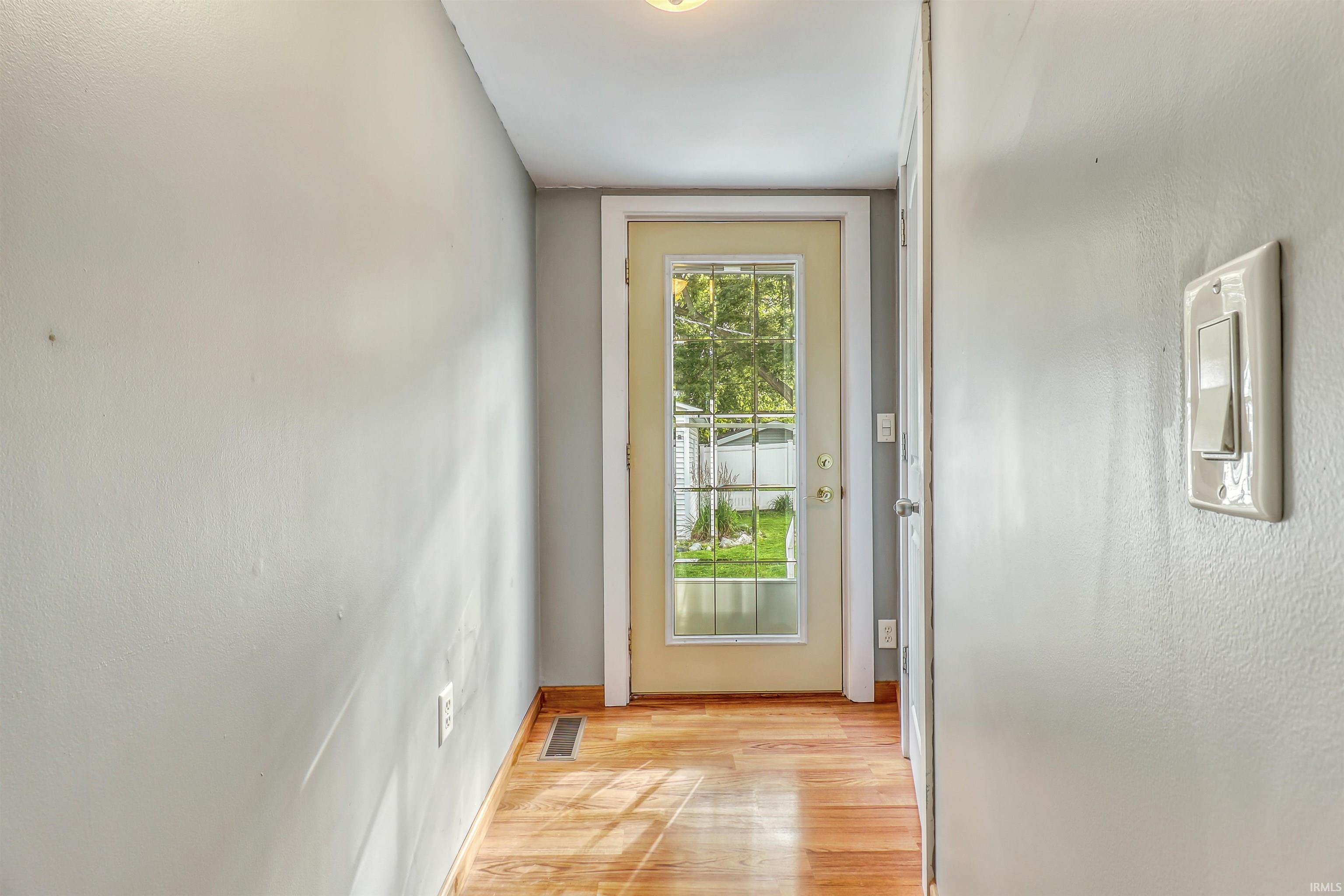 Entryway featuring wood-finish flooring, a full-lite door with grid panels, and light-colored walls