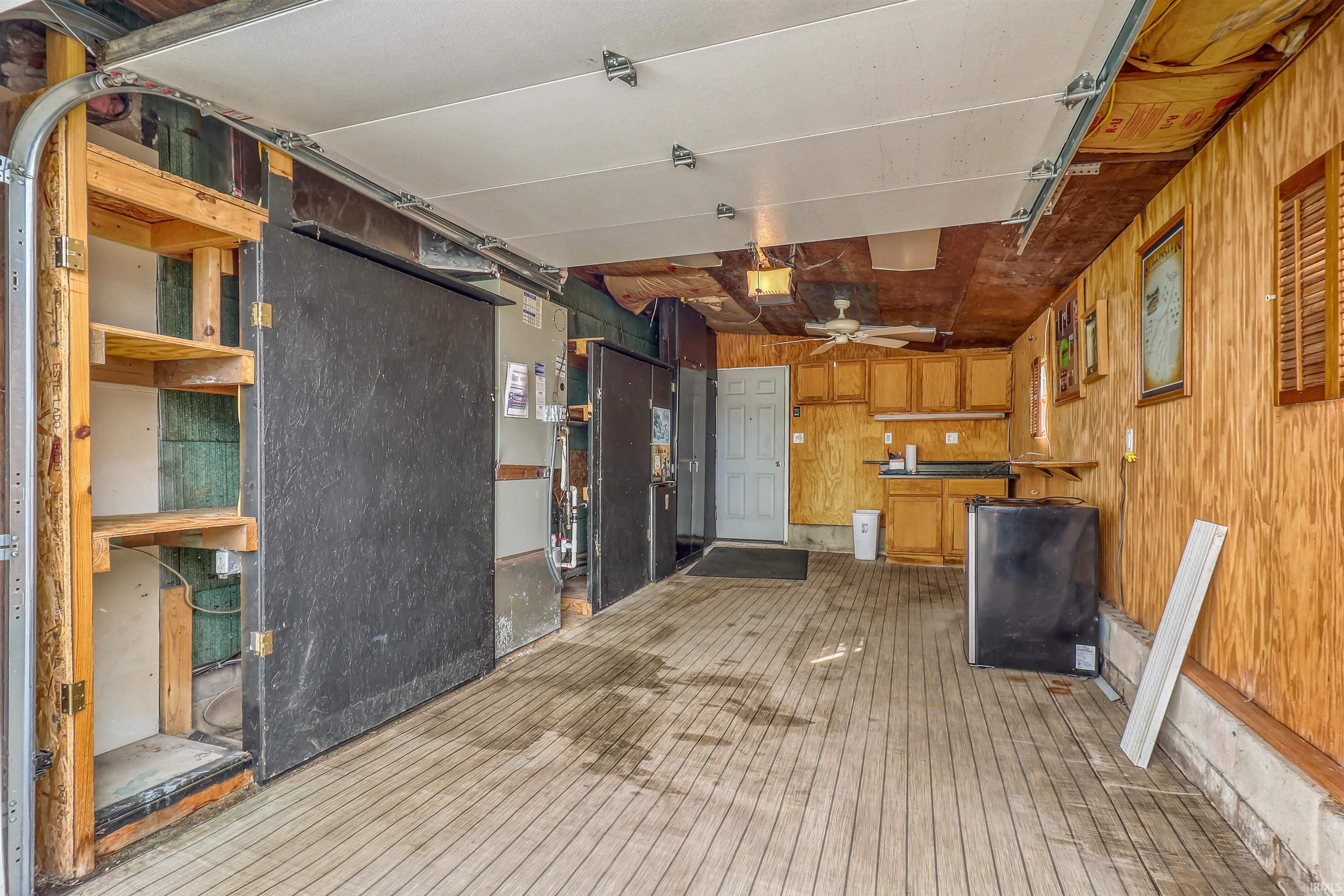 Spacious garage featuring wood-finish flooring, exposed wood-paneled walls, and built-in cabinetry