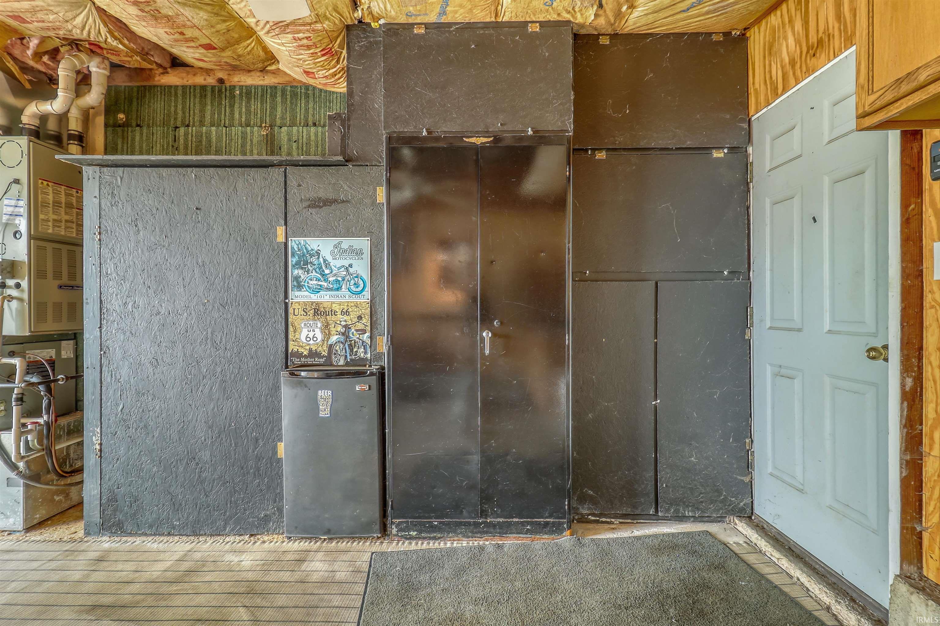 Utility area featuring a furnace unit, exposed ceiling insulation, and a white paneled door