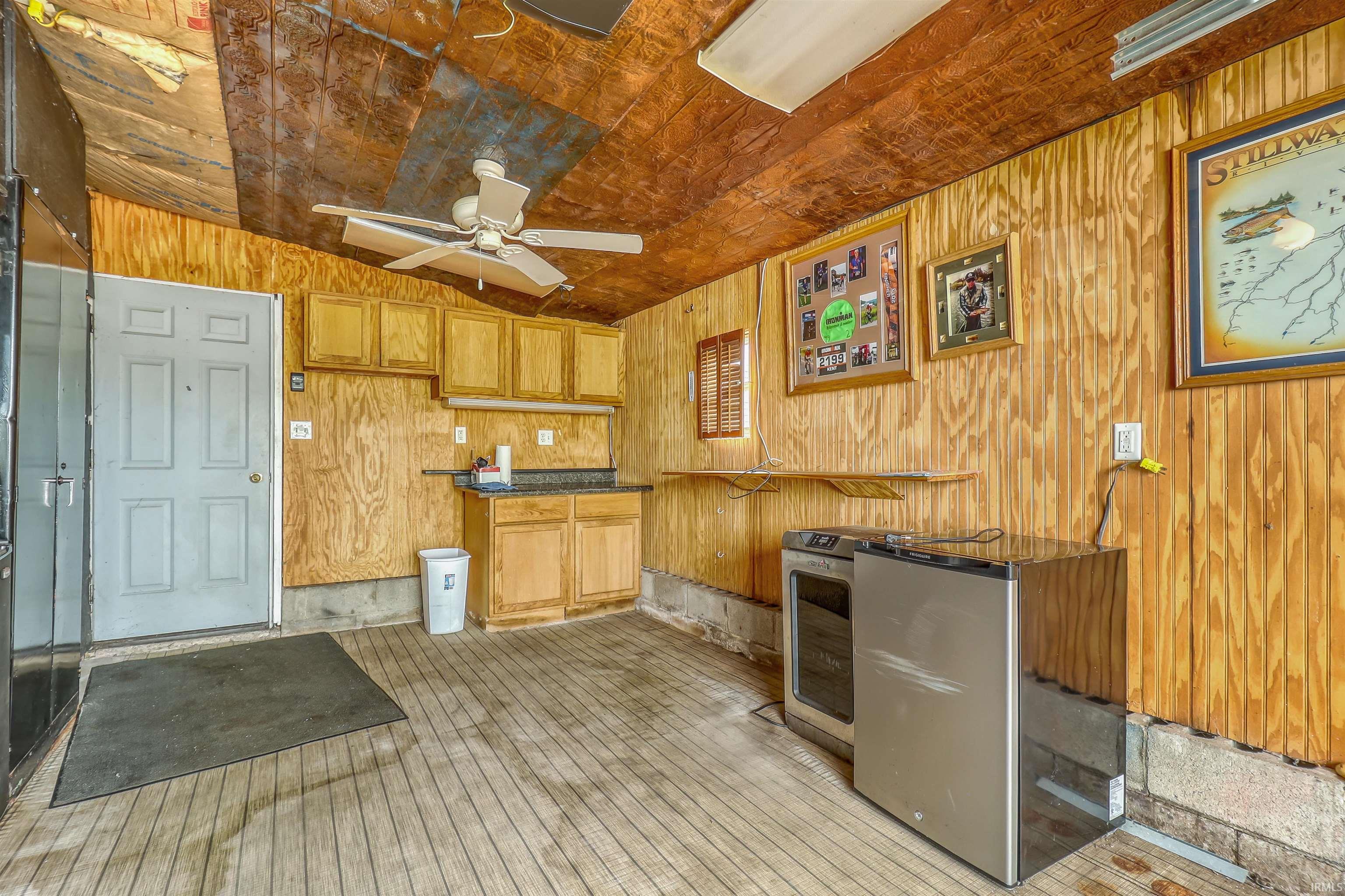 Utility space with wood-finish paneling, a ceiling fan, and built-in cabinetry featuring a countertop