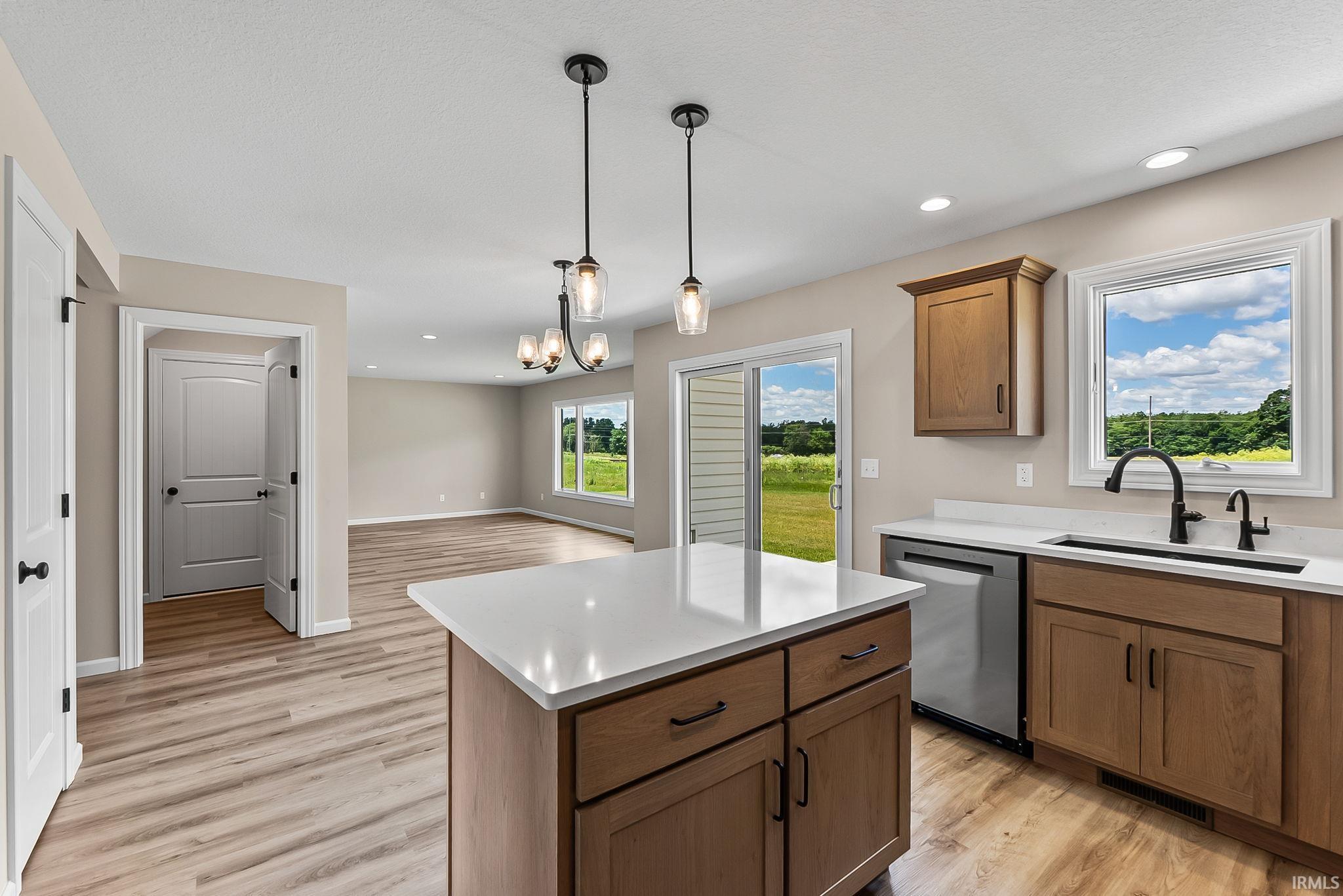 Open-concept kitchen featuring an island with a white countertop, wood-finish flooring, recessed lighting, and a sliding glass door