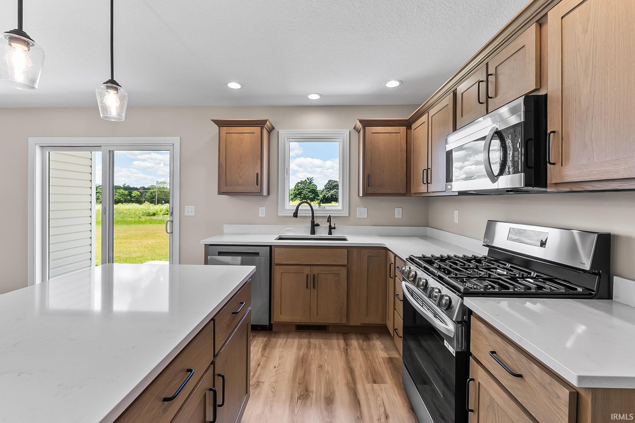 Modern kitchen featuring wood-finish cabinetry, light-toned countertops, and stainless steel appliances