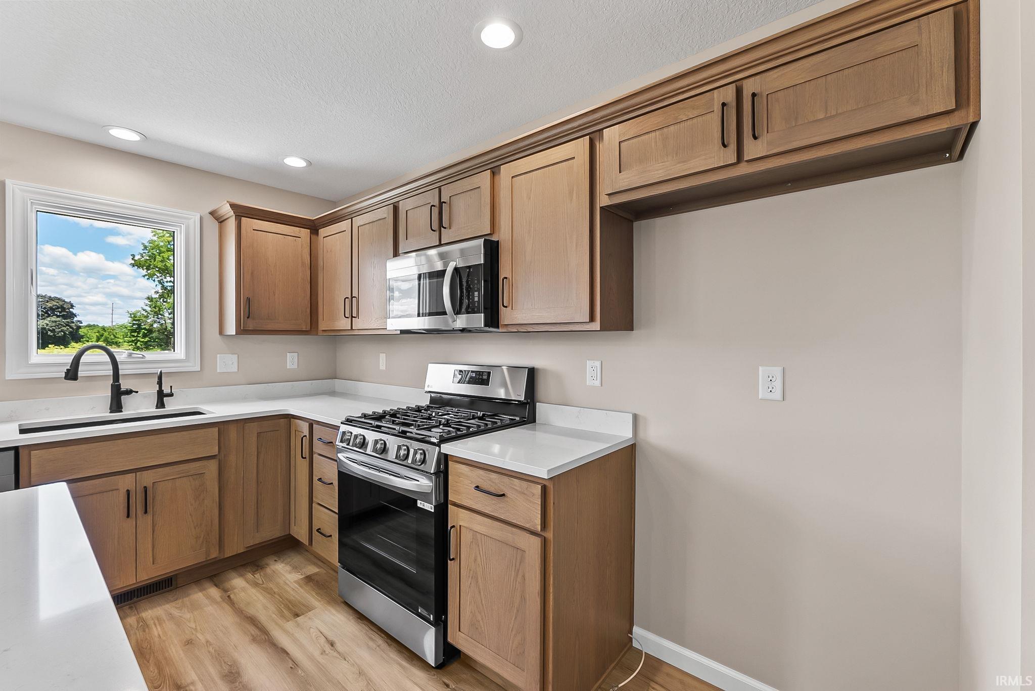 Kitchen featuring wood-finish cabinetry, light-toned countertops, and wood-finish flooring
