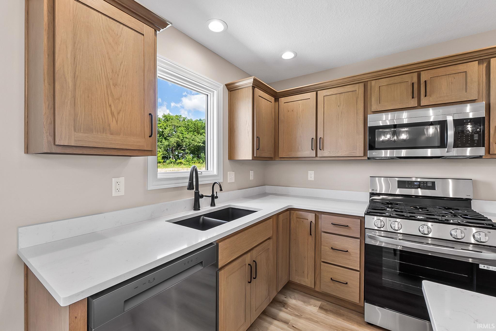 Kitchen featuring warm wood cabinetry, light countertops, and stainless steel appliances