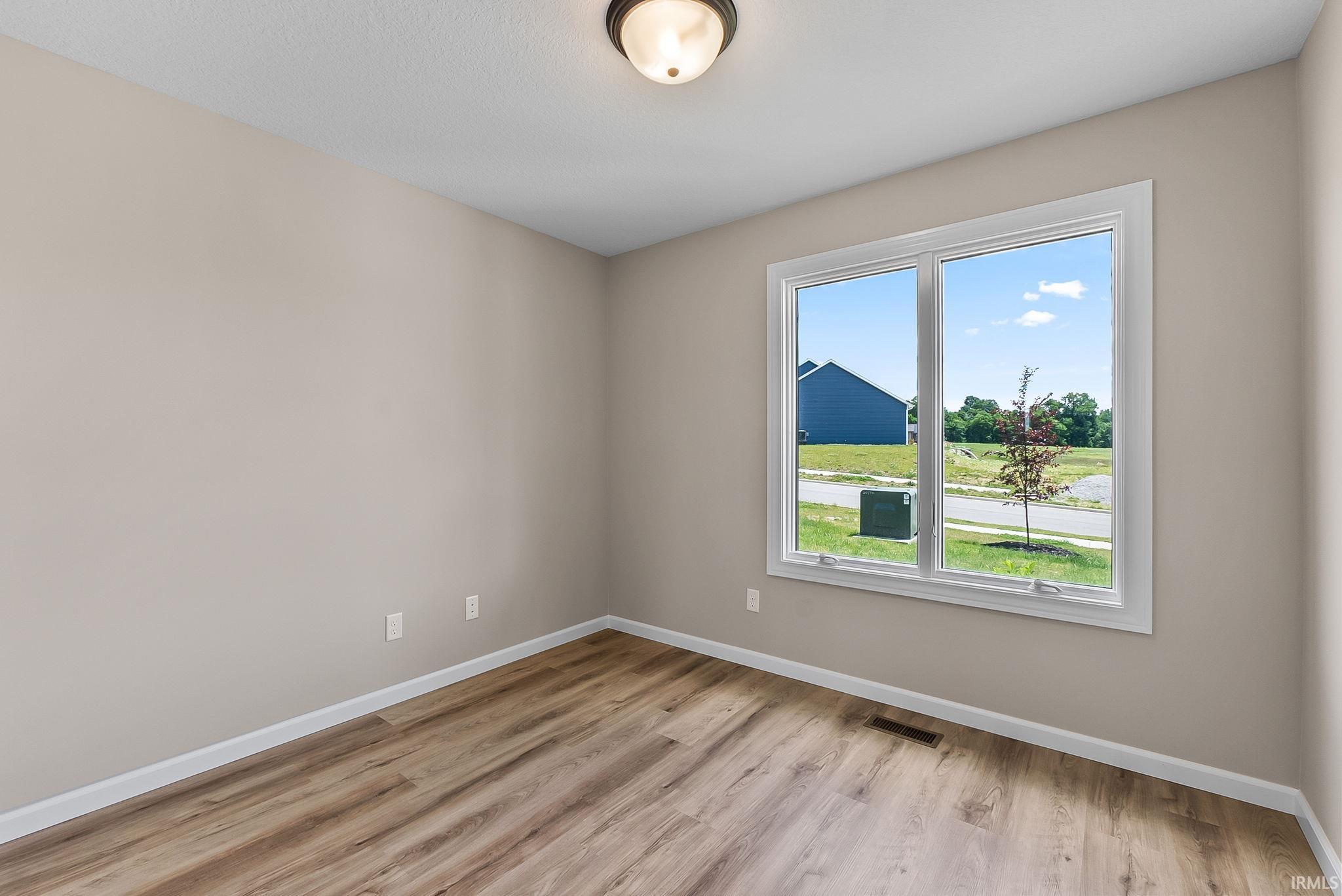 Interior room featuring light neutral walls and wood-finish flooring