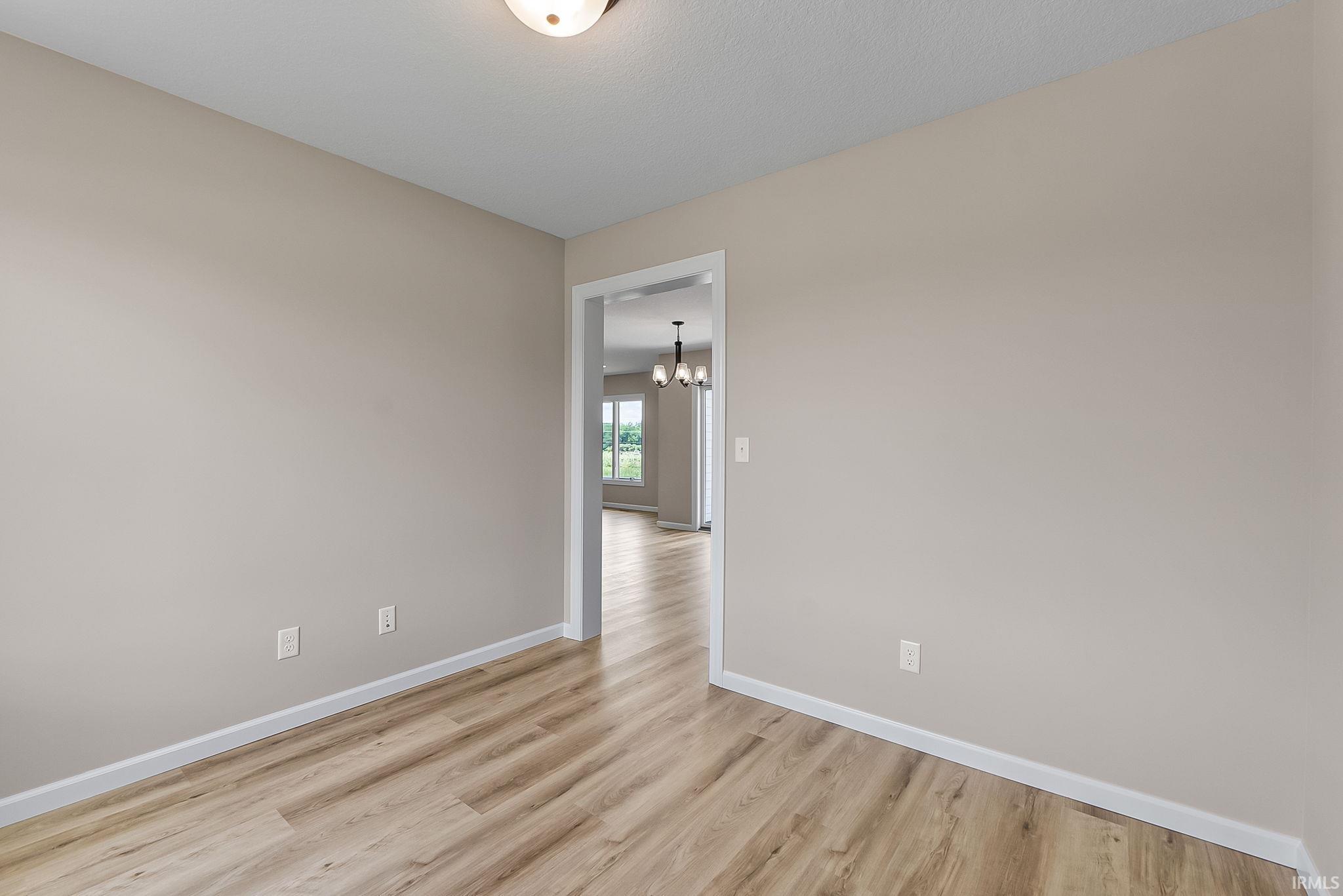 Interior room featuring wood-finish flooring, light neutral wall paint, and white baseboards
