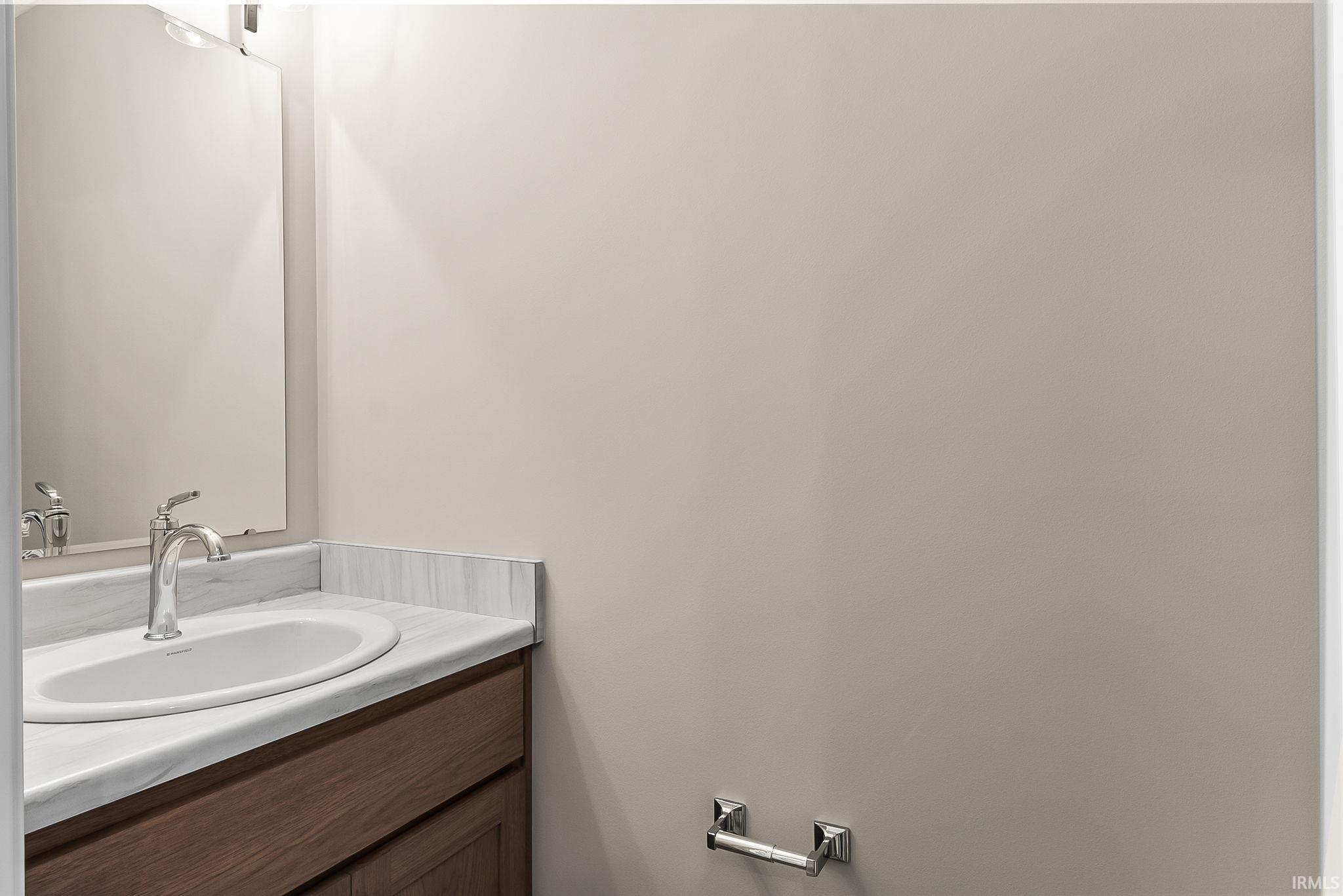 Vanity featuring a white oval sink with a chrome faucet, set into a stone-look countertop with matching backsplash
