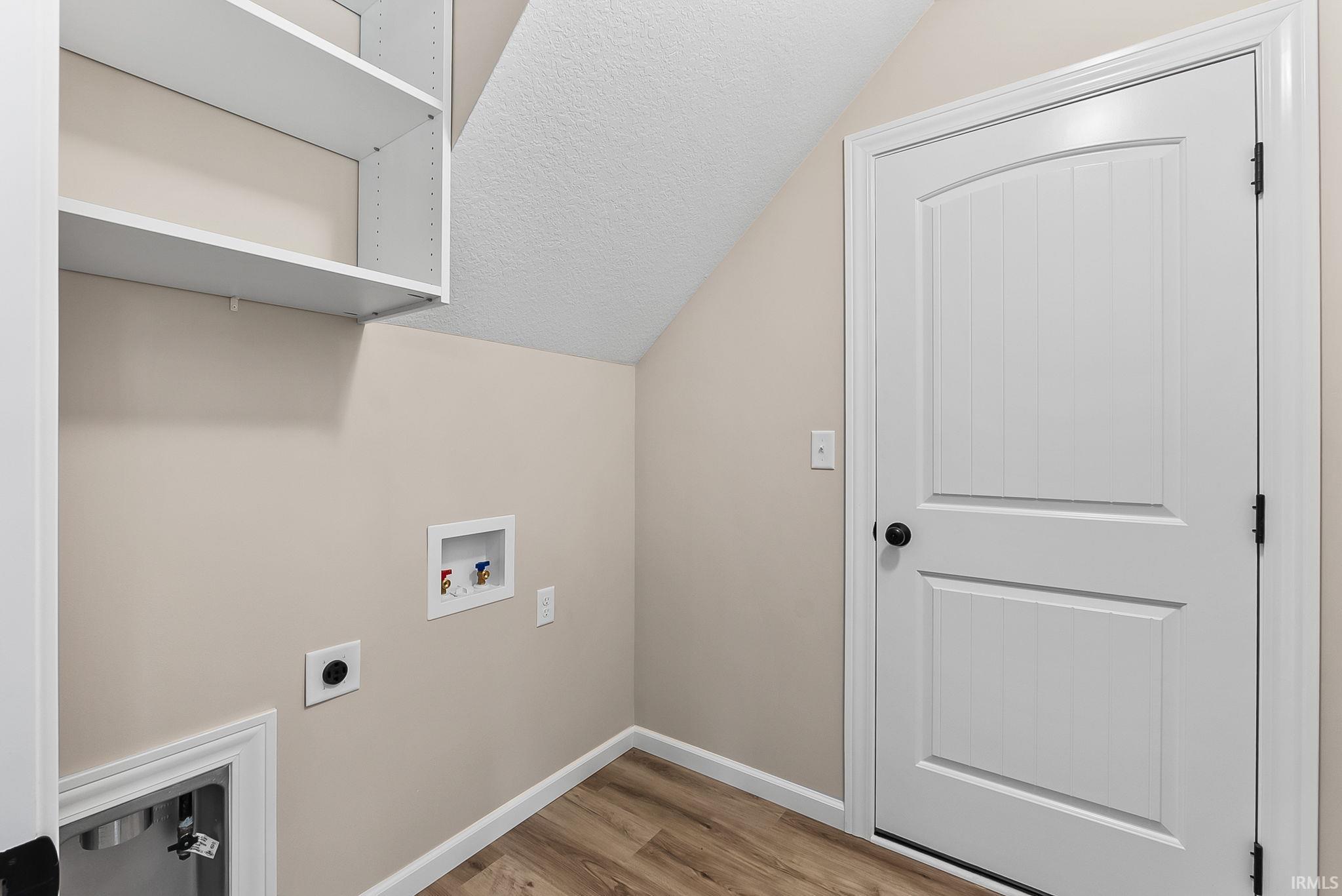 Utility area featuring wood-finish flooring, white baseboards, and neutral wall paint