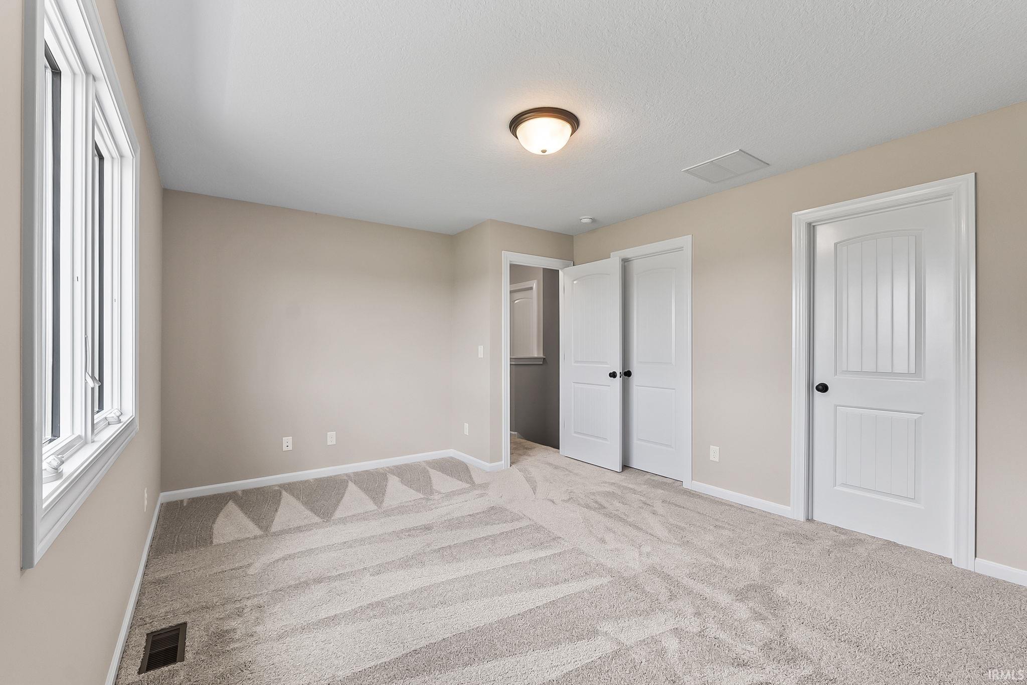 Neutral-toned walls complement the light-colored patterned carpeting