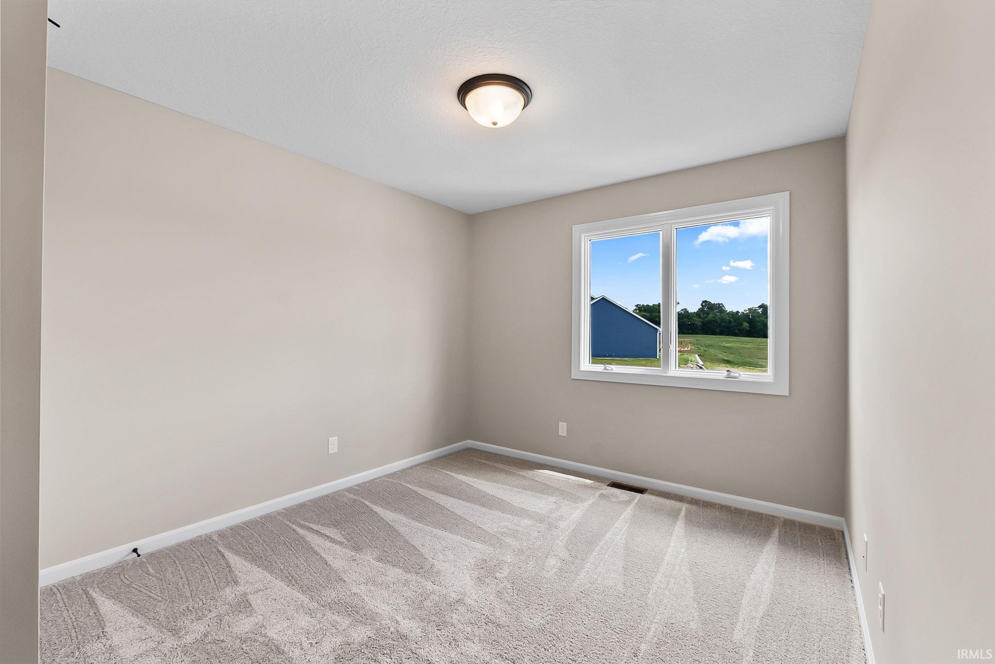 Carpeted room with neutral wall paint and a single window offering exterior views