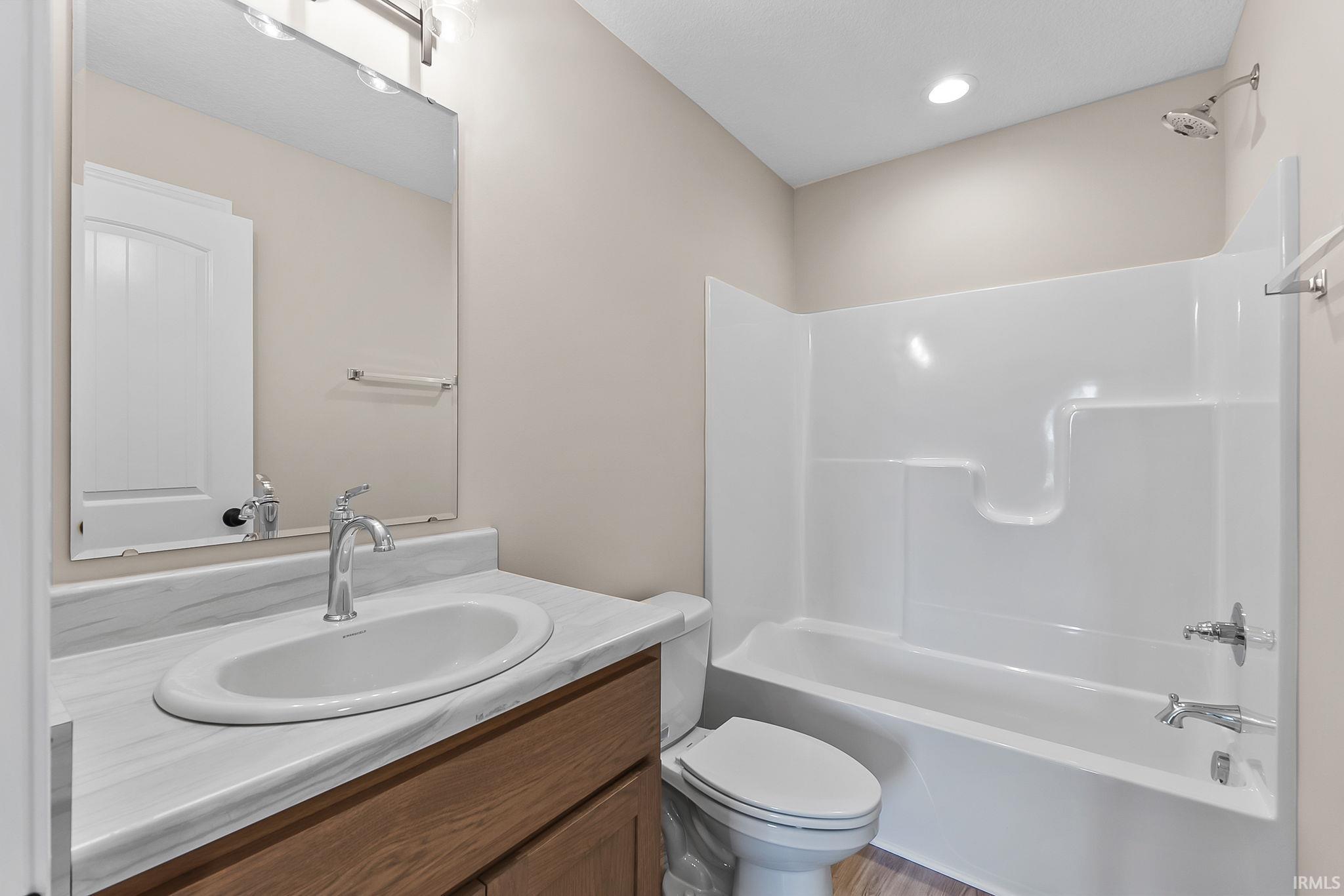 Bathroom featuring a wood-finish vanity with an integrated sink and a white countertop