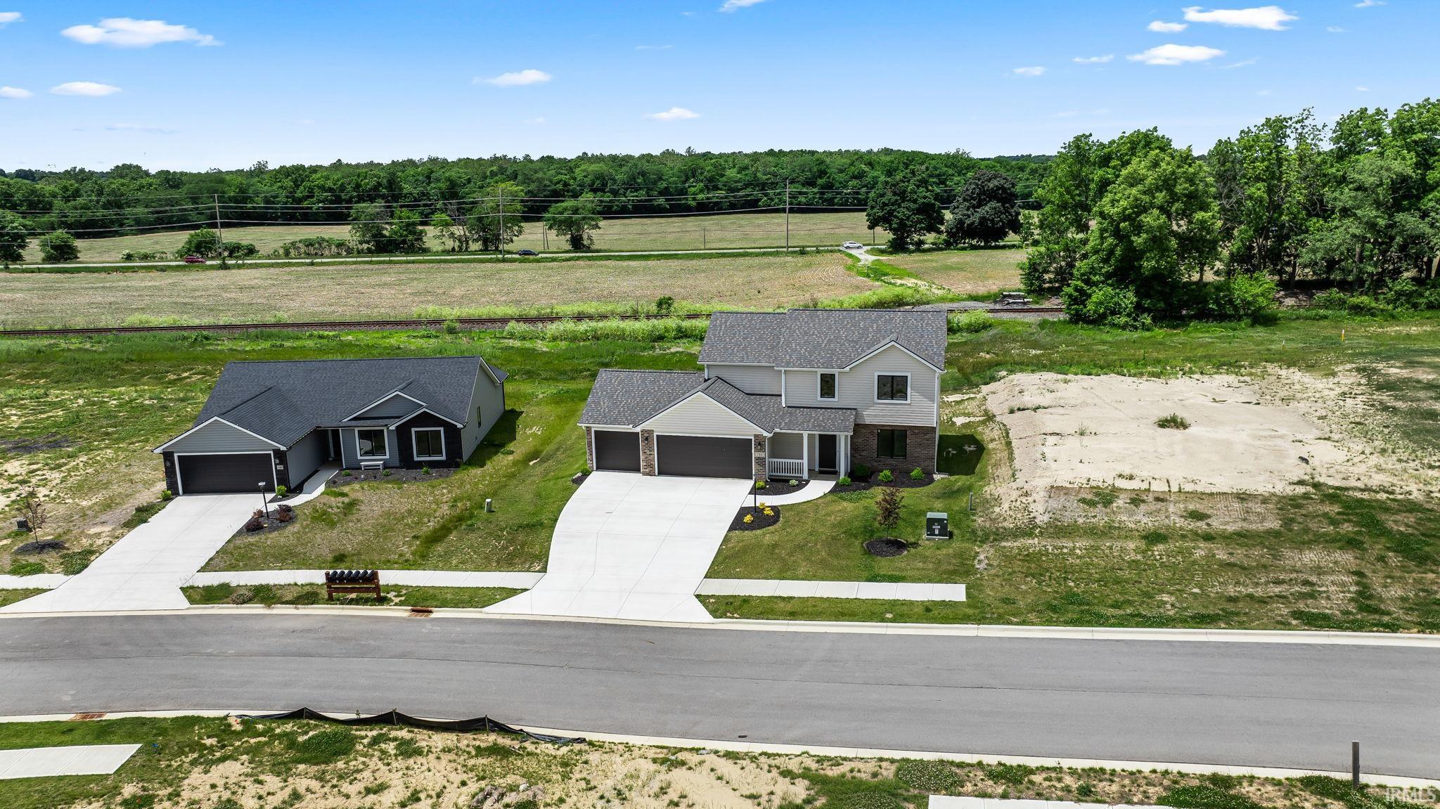 Newly constructed residence featuring a light gray exterior with brick accents, an attached two-car garage, and a concrete driveway