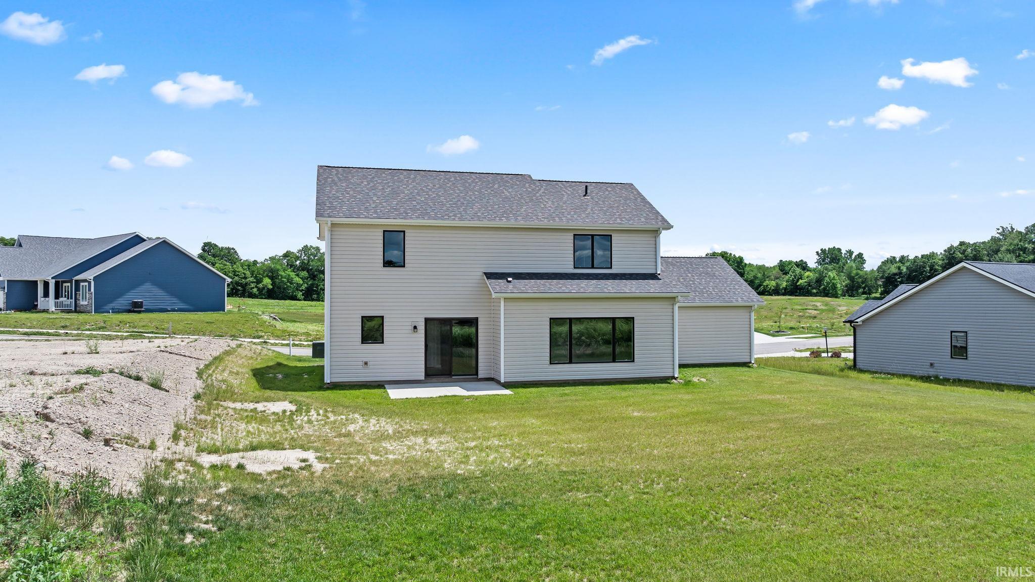 Rear exterior featuring light-colored siding, a dark shingle roof, and multiple large windows