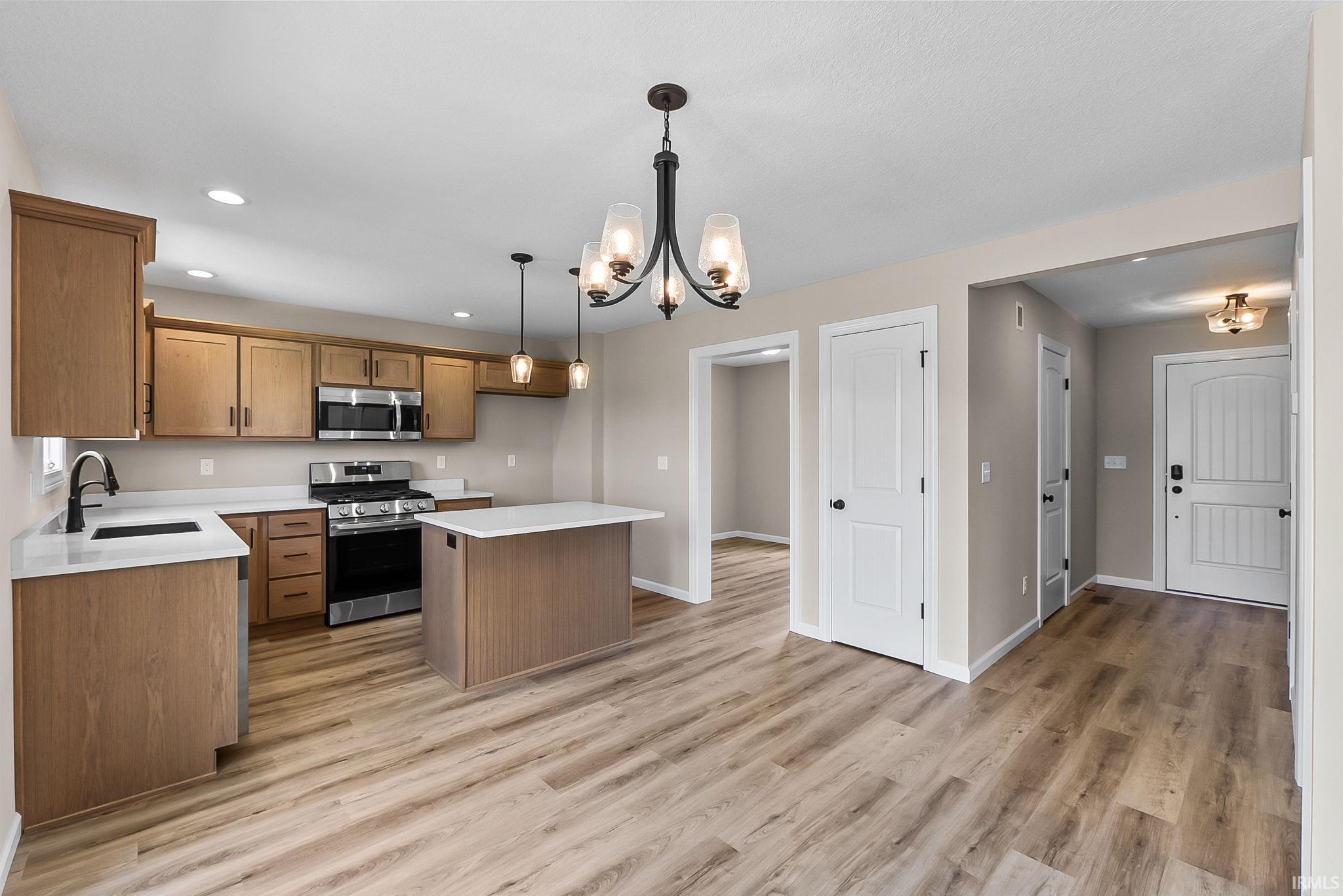 Kitchen featuring wood-finish cabinetry, stainless steel appliances, and a central island with white countertop