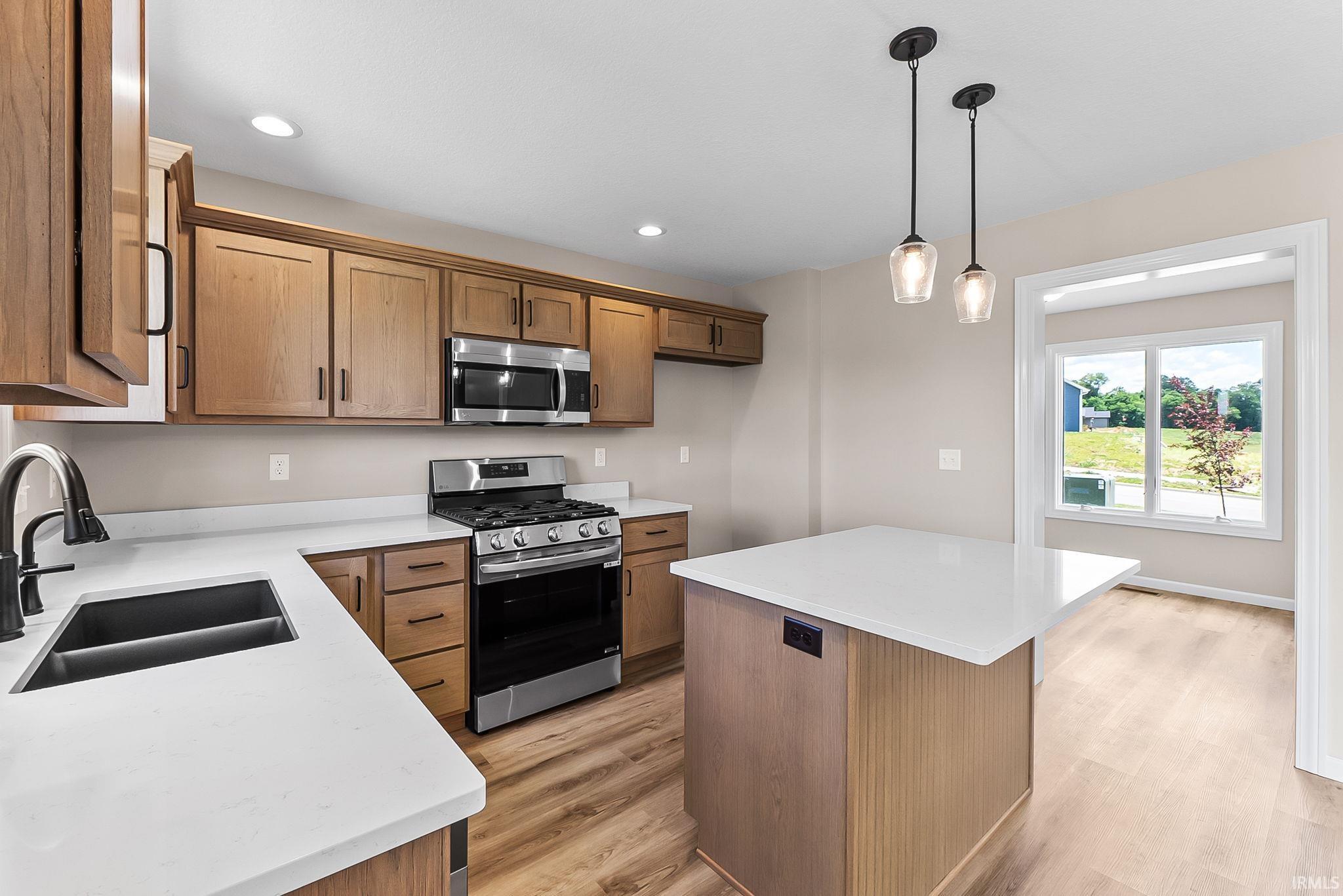 Modern kitchen featuring wood-finish cabinetry, stainless steel appliances, and a central island with a solid surface countertop