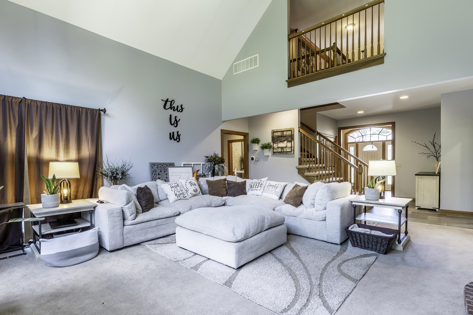 Spacious living area featuring vaulted ceilings, a carpeted floor, and a two-story architectural design