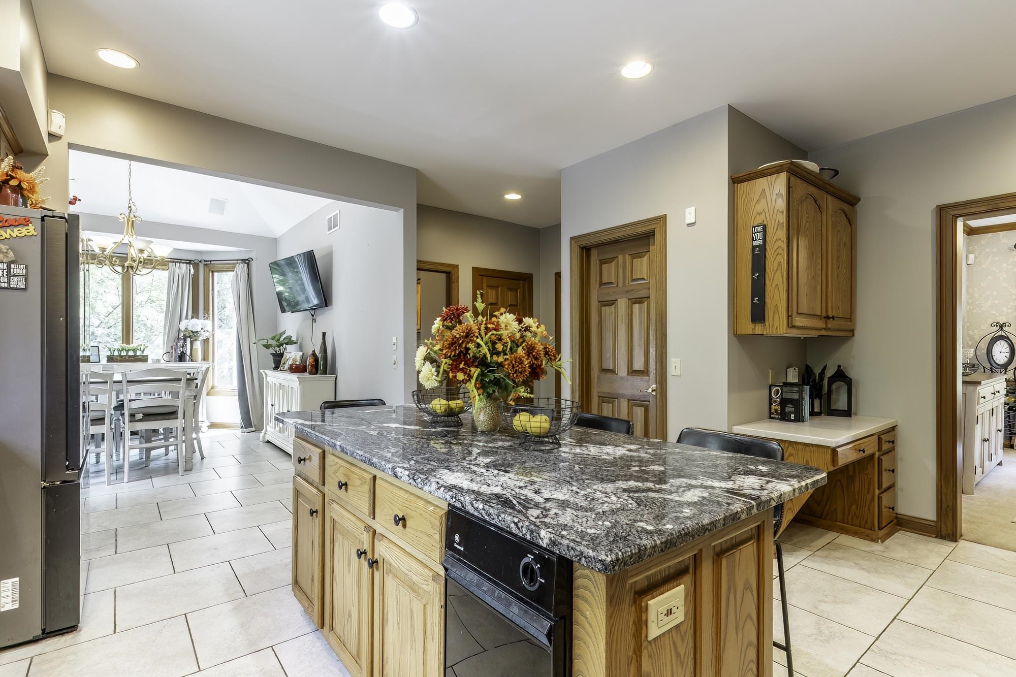Kitchen featuring a large central island with a granite countertop, wood cabinetry, and integrated dishwasher
