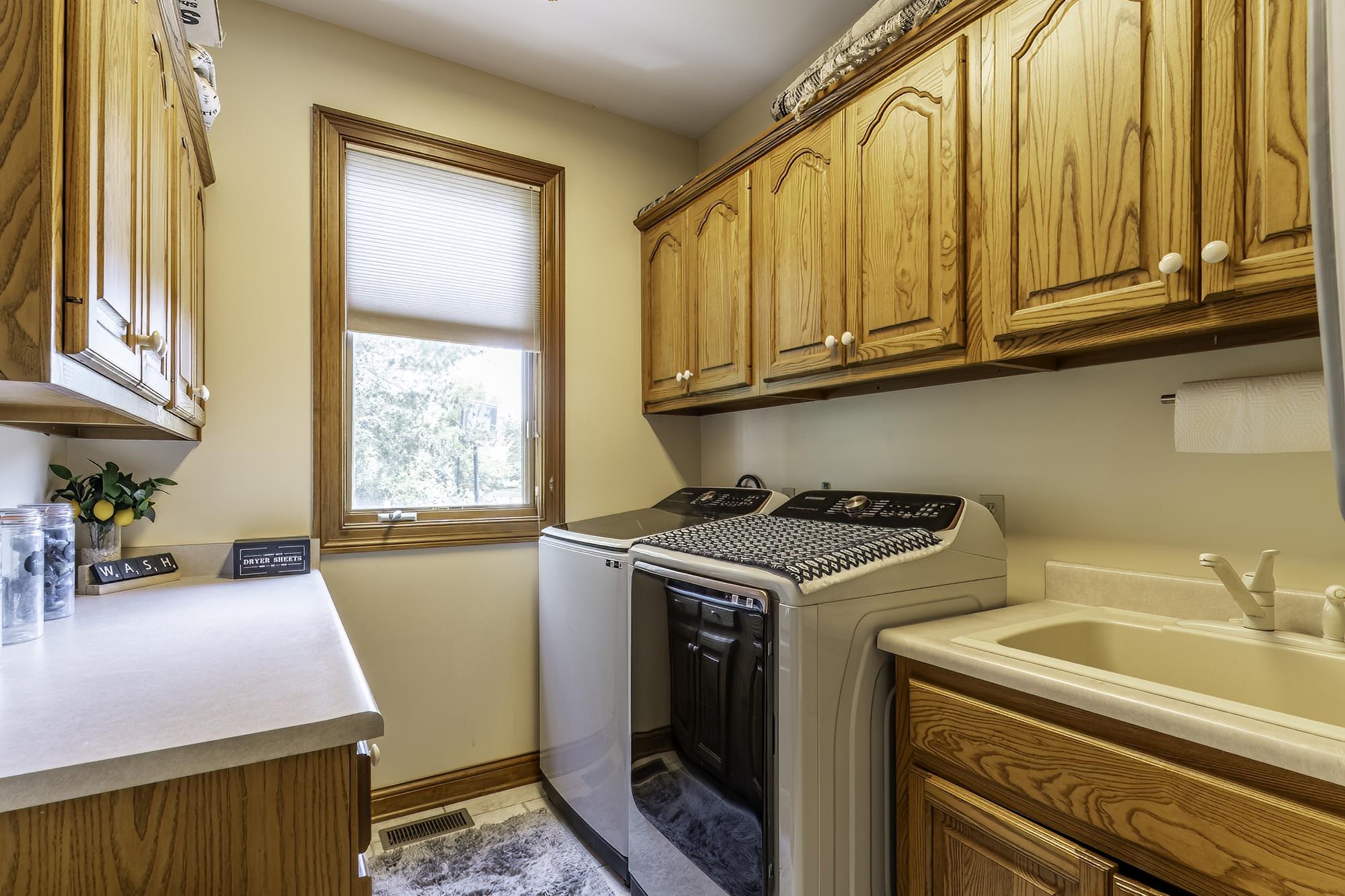 Utility room with extensive wood cabinetry, a utility sink, and ample countertop space