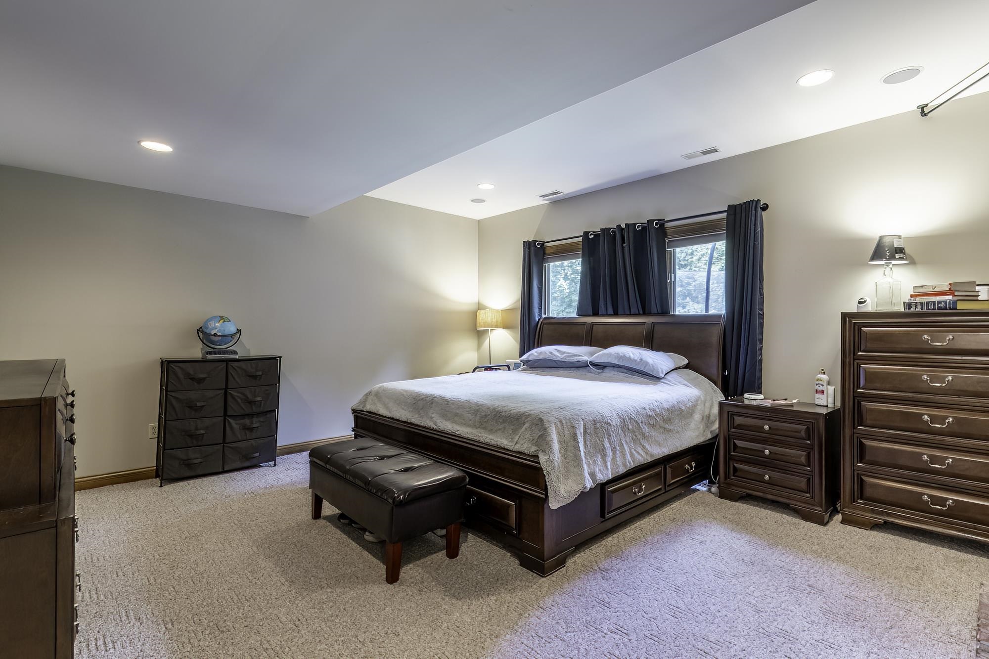 Carpeted bedroom featuring recessed lighting, a window with dark curtains, and light-toned walls