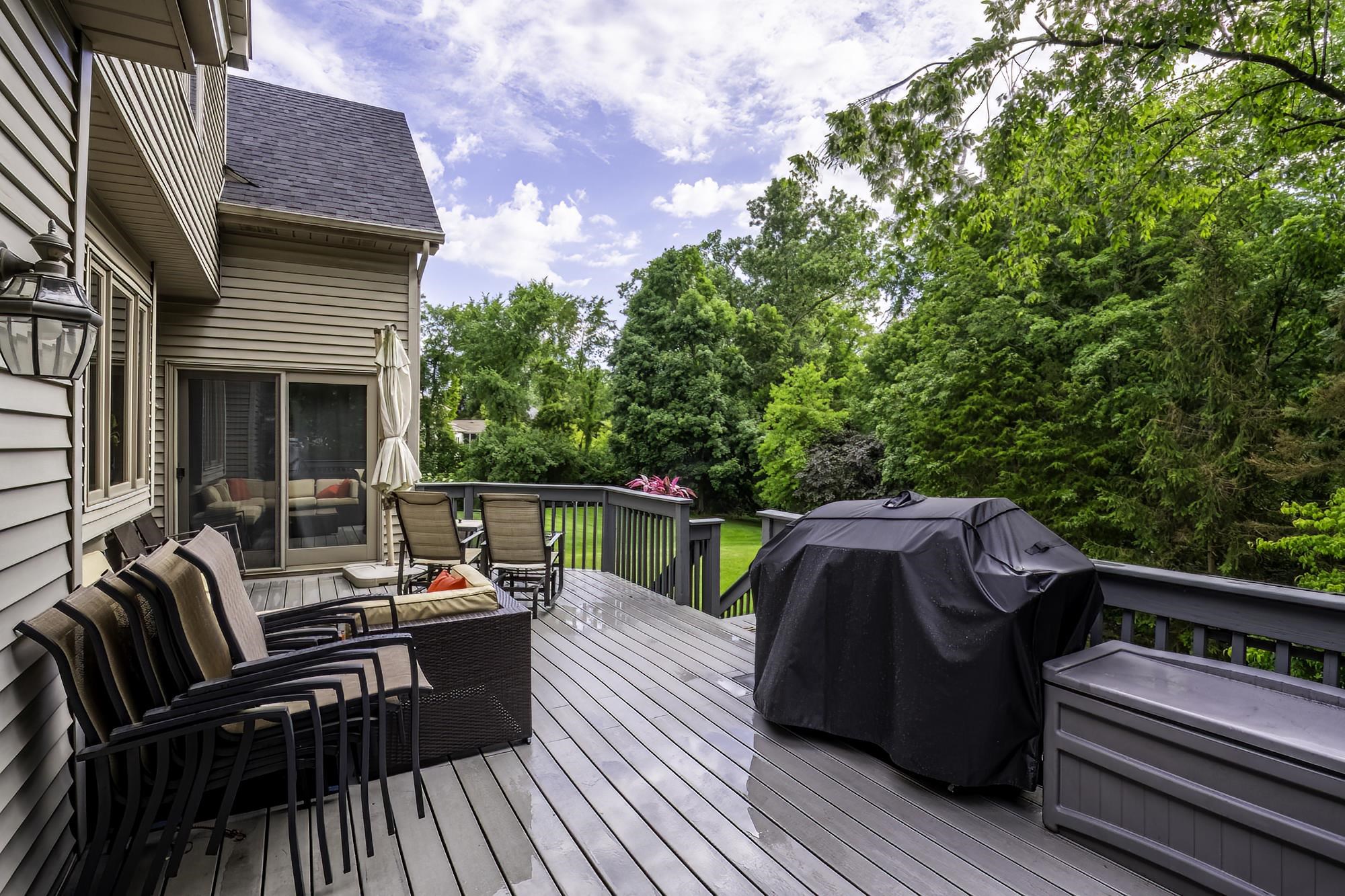 Expansive outdoor deck featuring wood-finish flooring, dark grey railing, and direct access through a sliding glass door