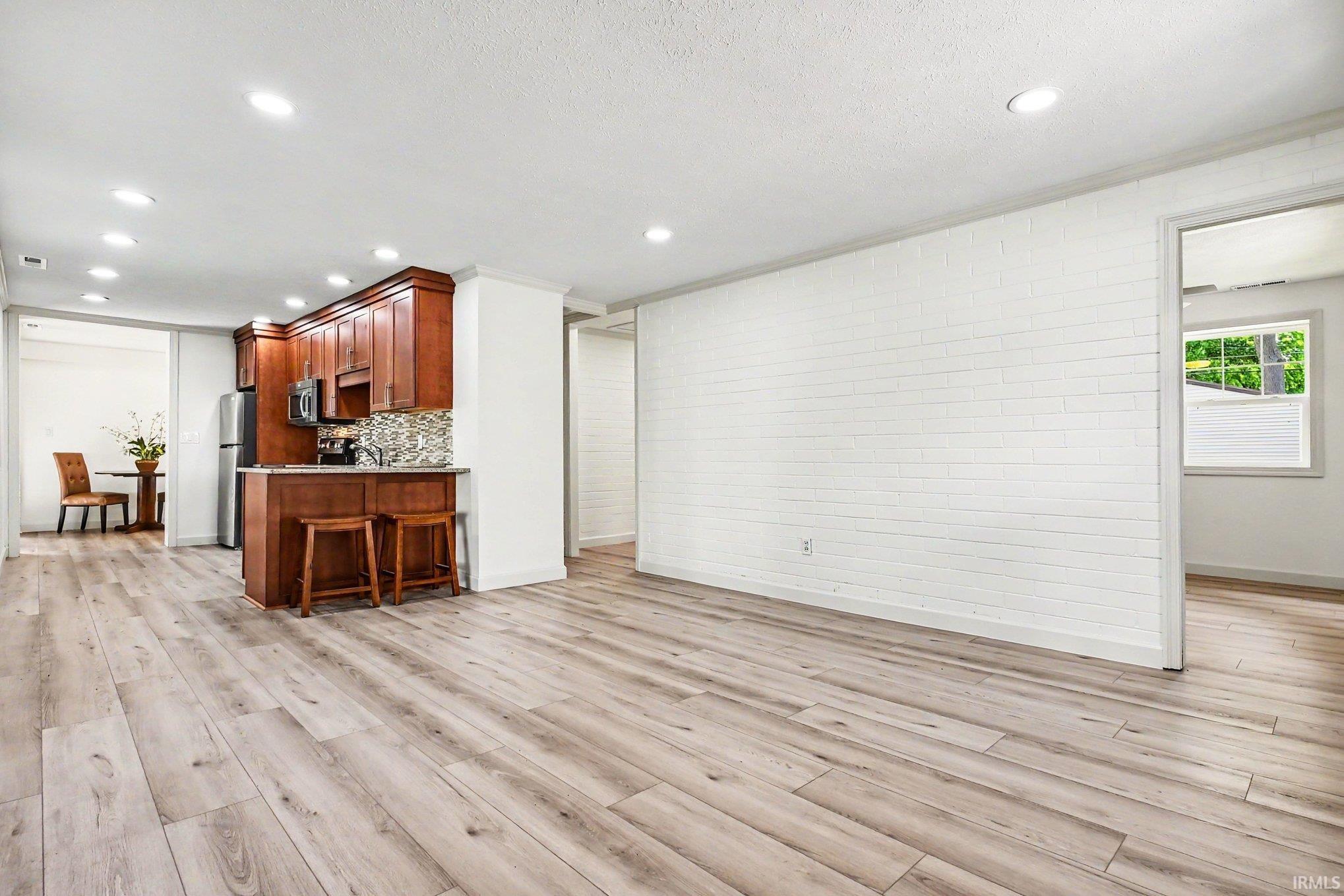 Spacious open concept area featuring wood-finish flooring, recessed lighting, and a white shiplap accent wall