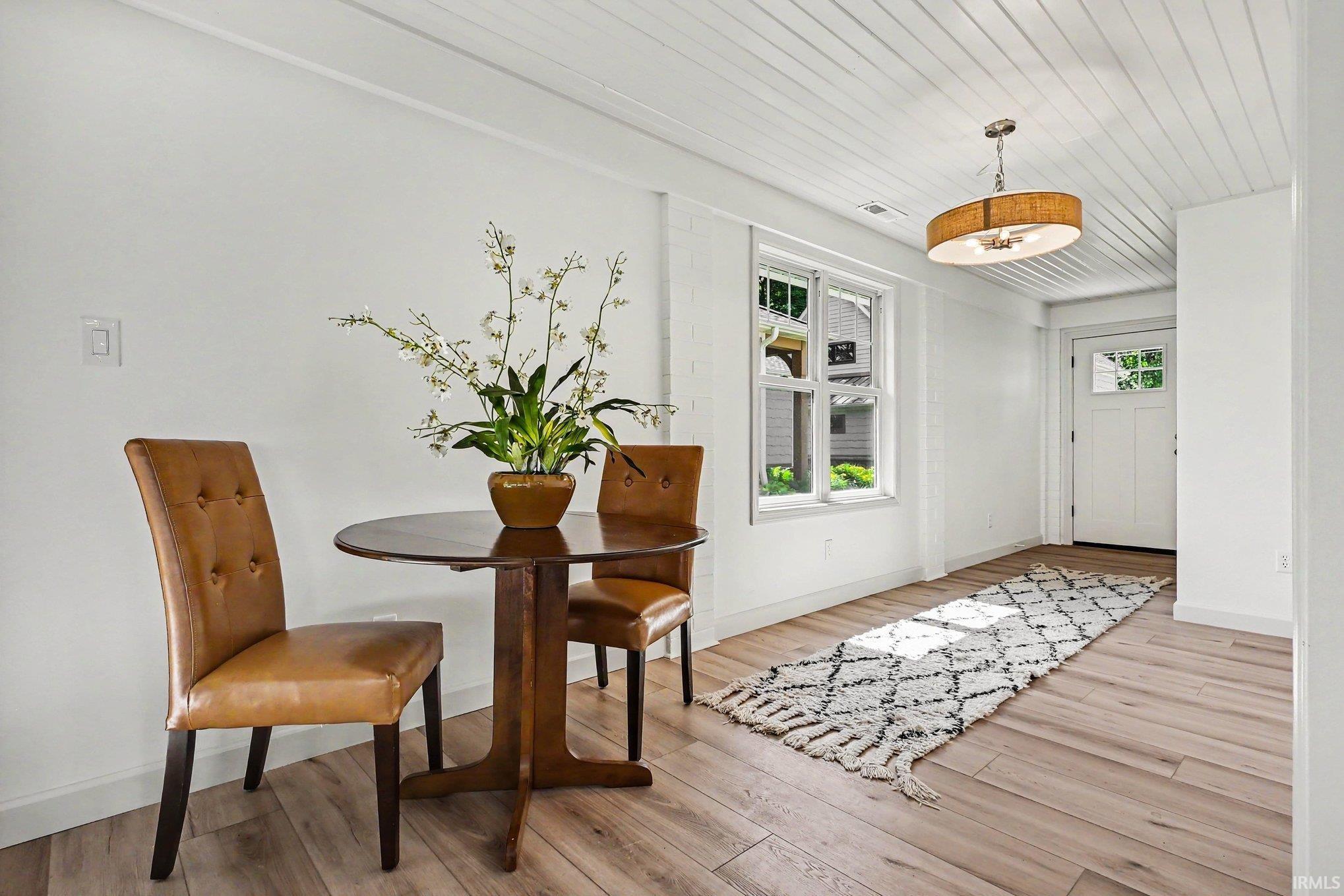 Bright entry area with wood-finish flooring, white shiplap ceiling, and a multi-pane entry door