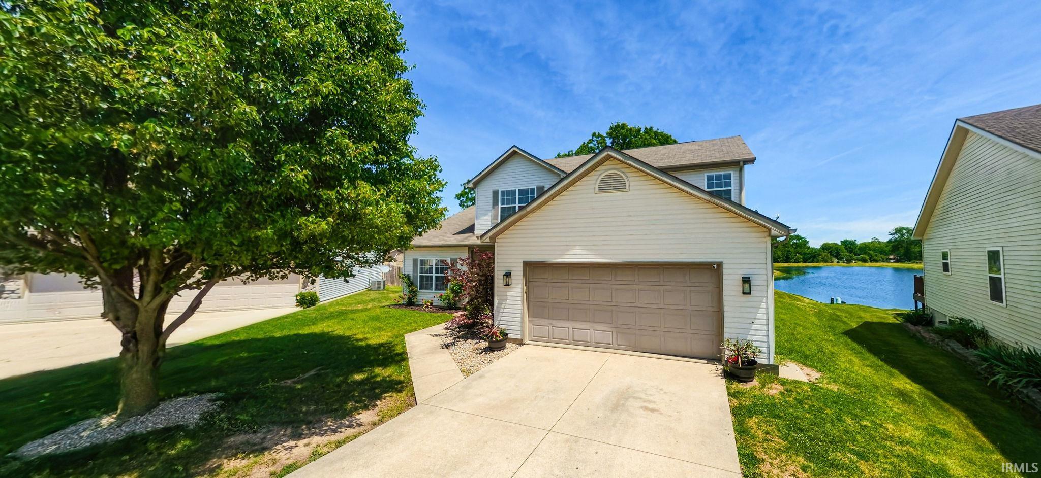 Traditional two-story residence featuring light-colored siding, an attached two-car garage, and a concrete driveway
