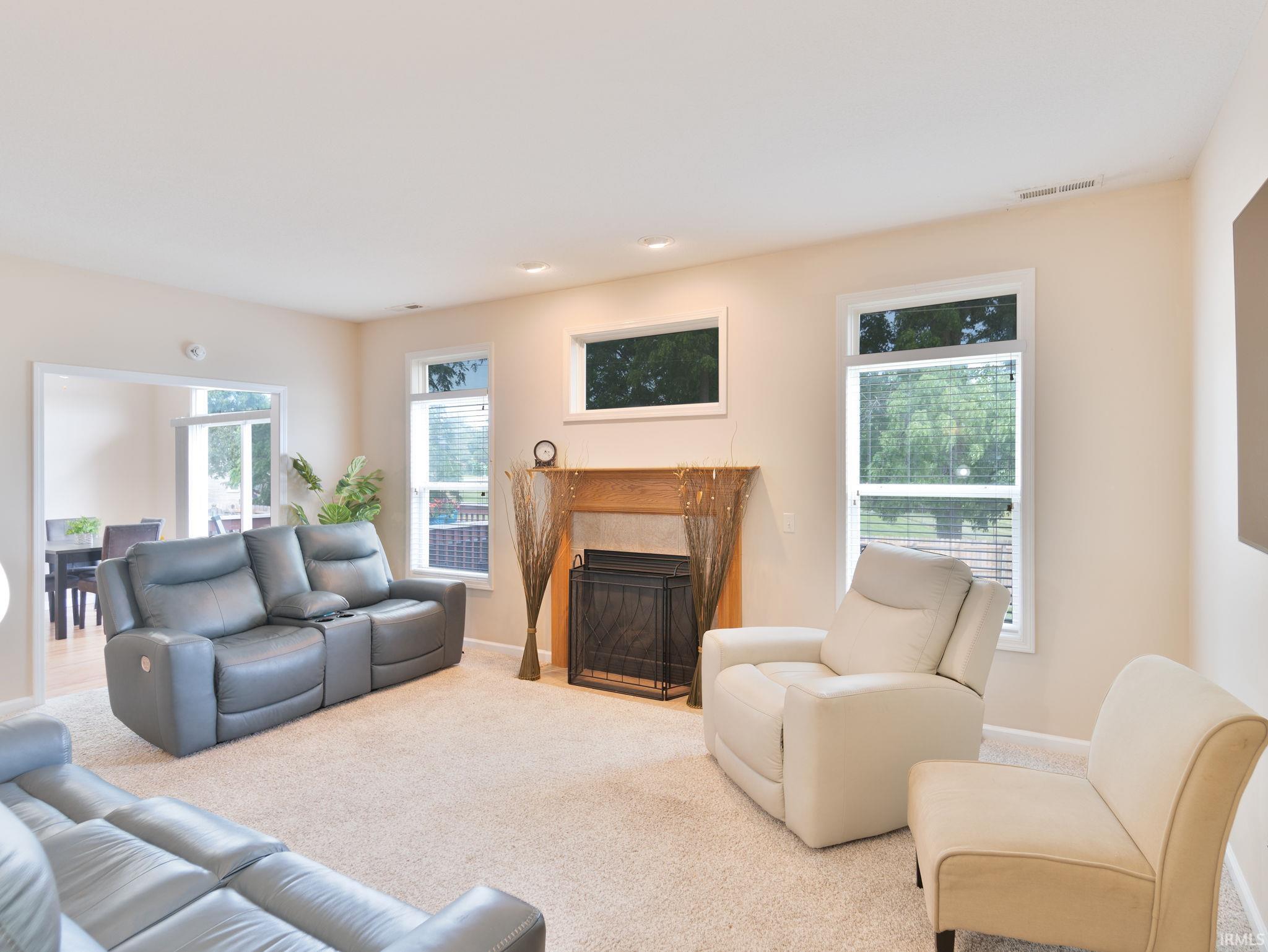 Living area featuring a fireplace with a wood-finish mantel, neutral-tone walls, recessed lighting, and carpet flooring