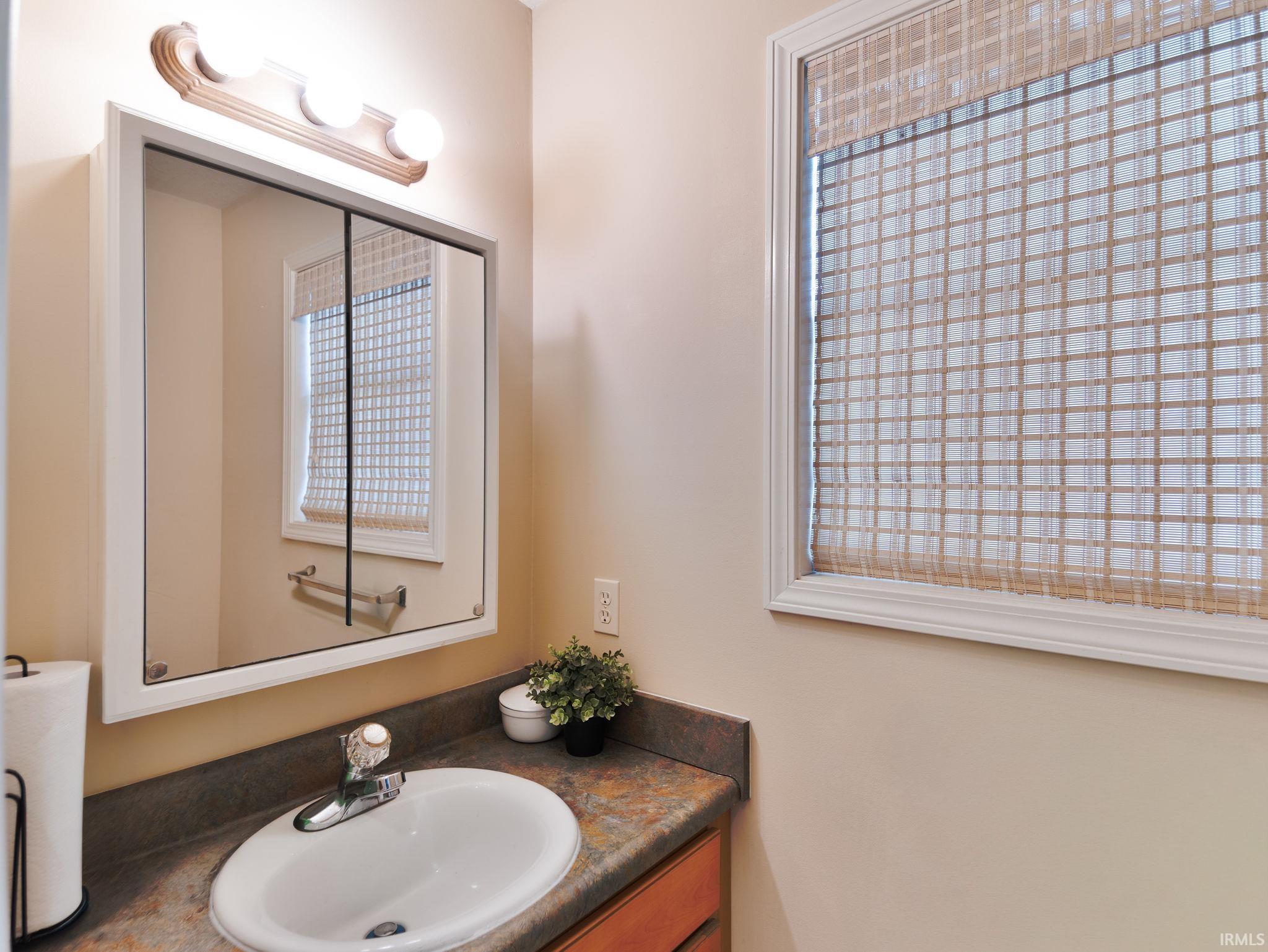 Bathroom vanity featuring a white oval sink, chrome faucet, and a laminate countertop