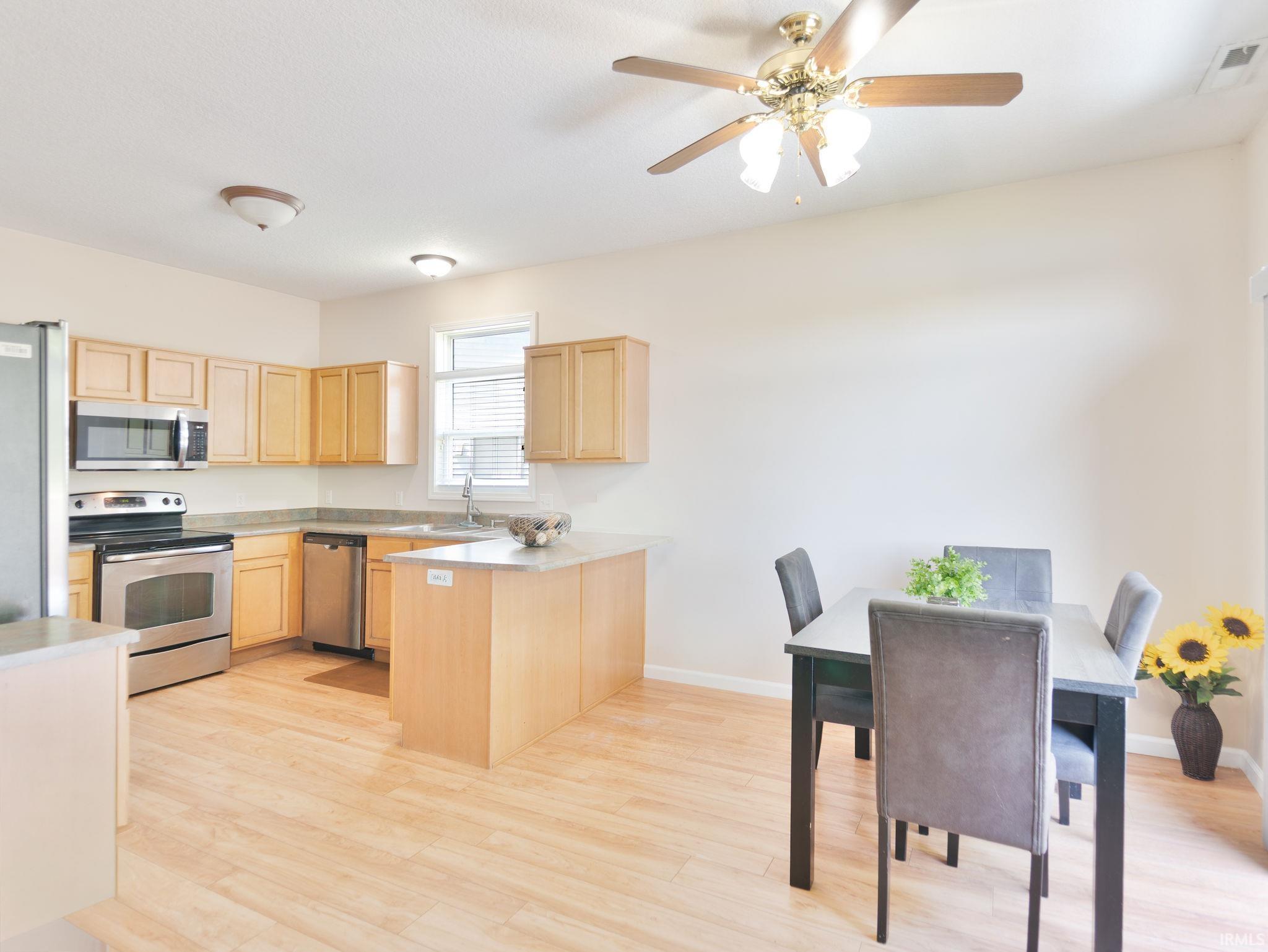 Open-concept kitchen and dining area featuring light wood-finish flooring