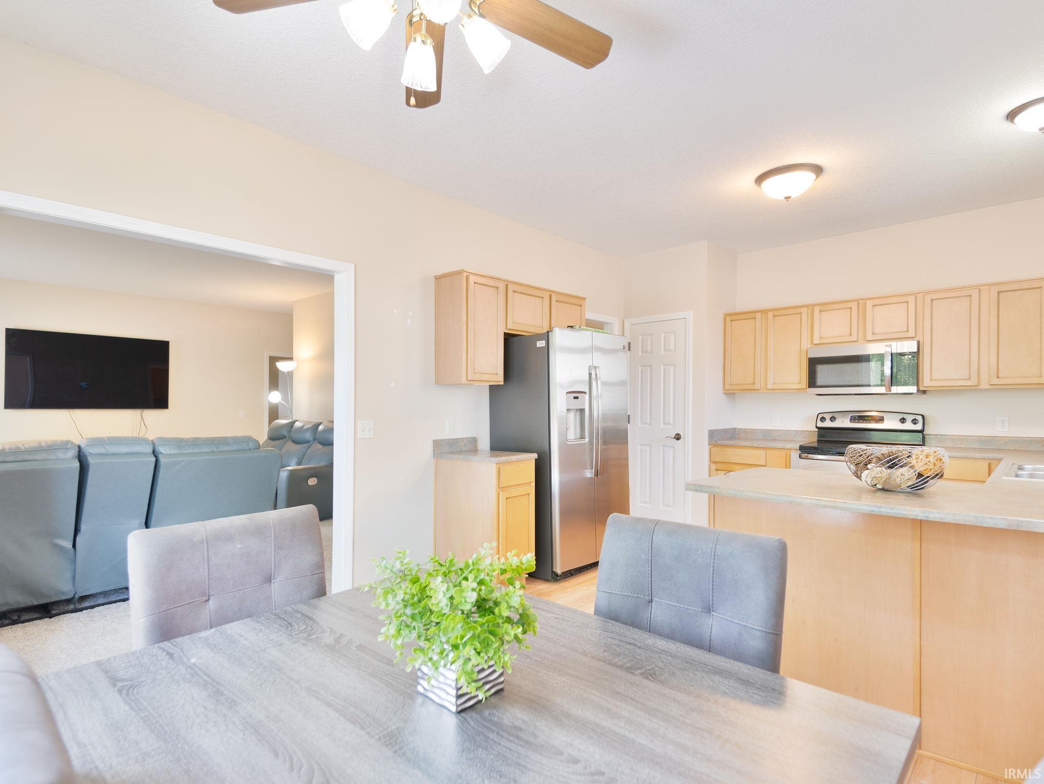 Kitchen featuring light wood-finish cabinetry, stainless steel appliances, and a peninsula countertop