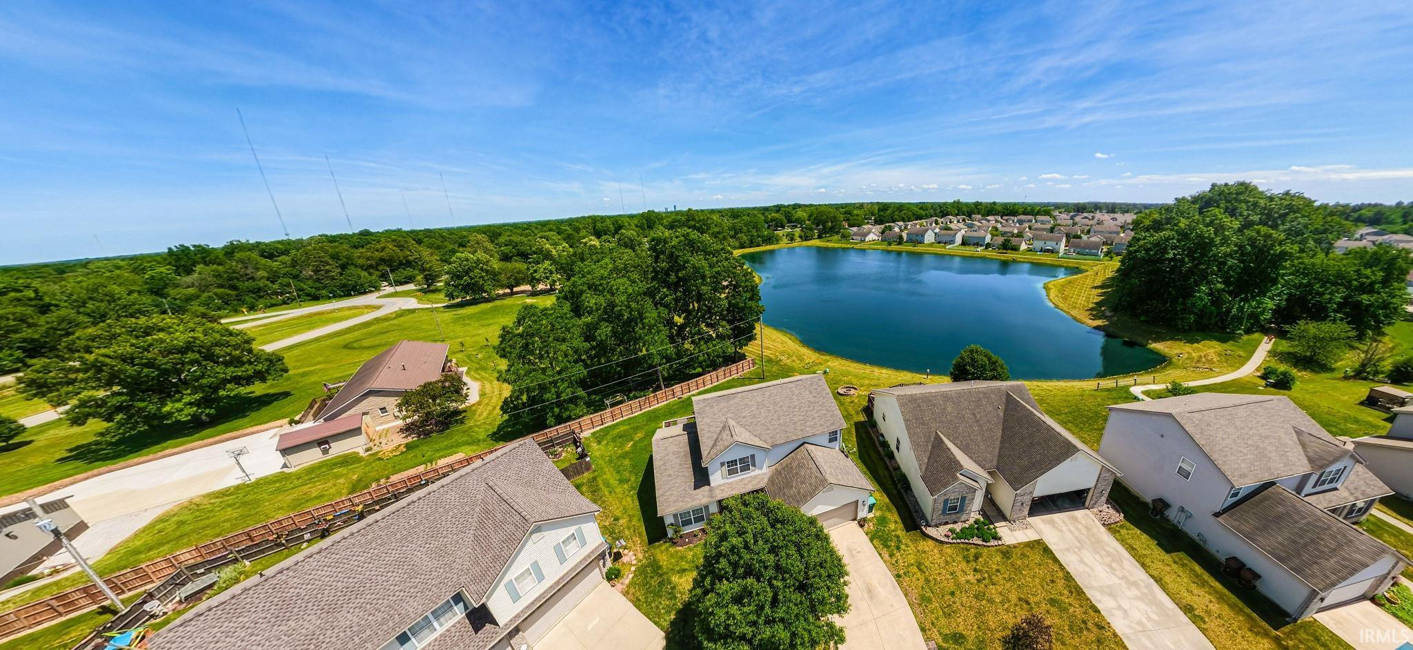 Residential community featuring a prominent pond surrounded by mature trees and residential properties